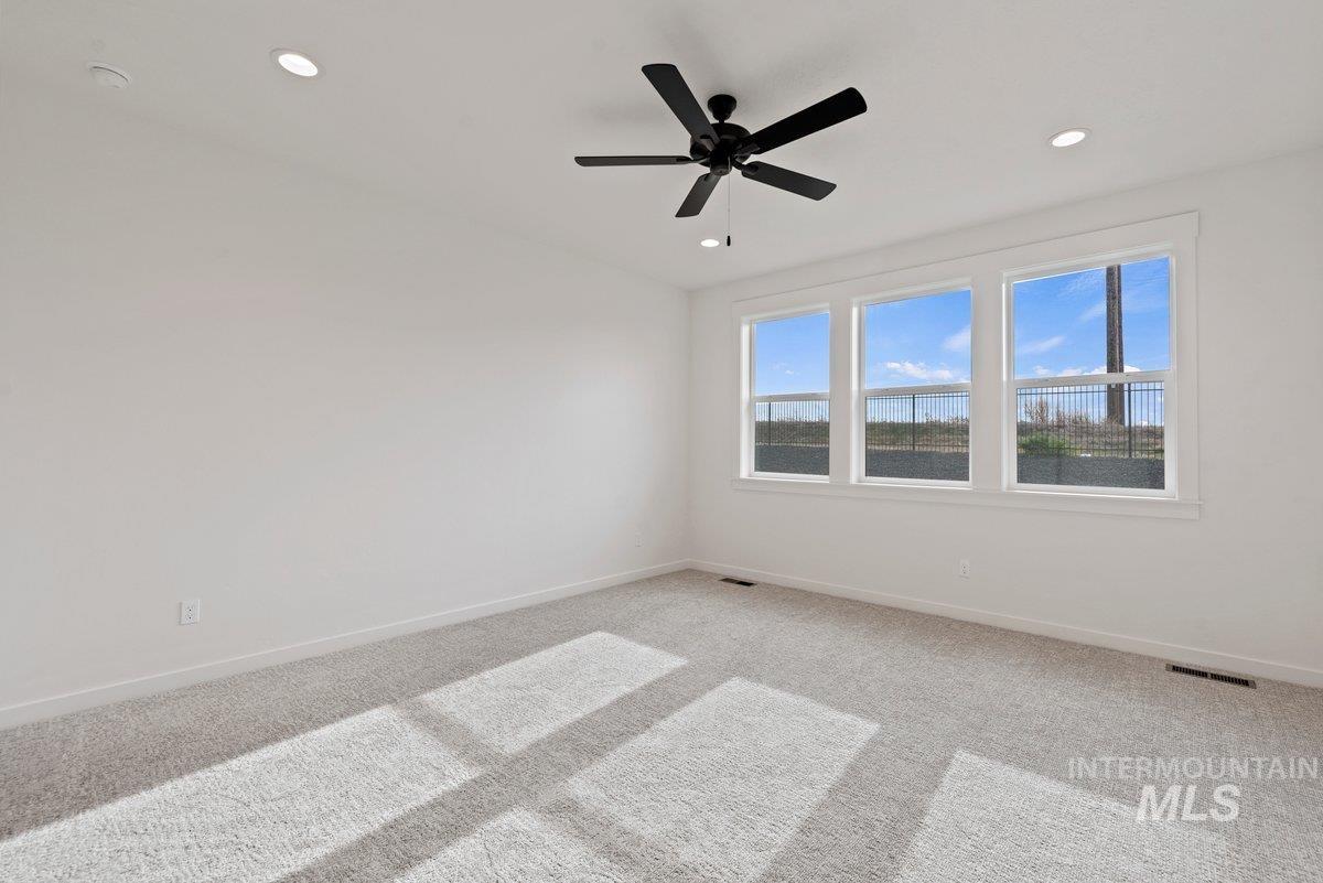 Carpeted empty room featuring ceiling fan and recessed lighting