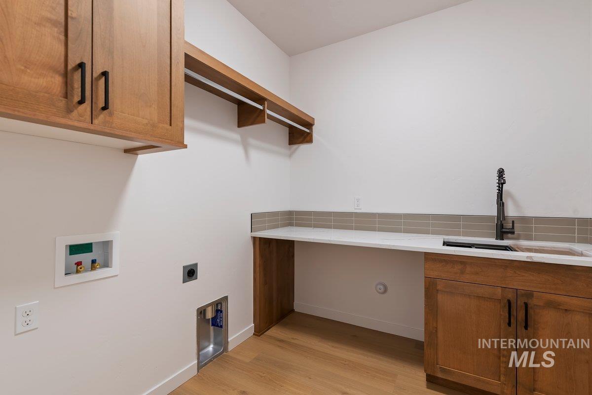Washroom with cabinet space, light wood-style flooring, hookup for a washing machine, and hookup for an electric dryer