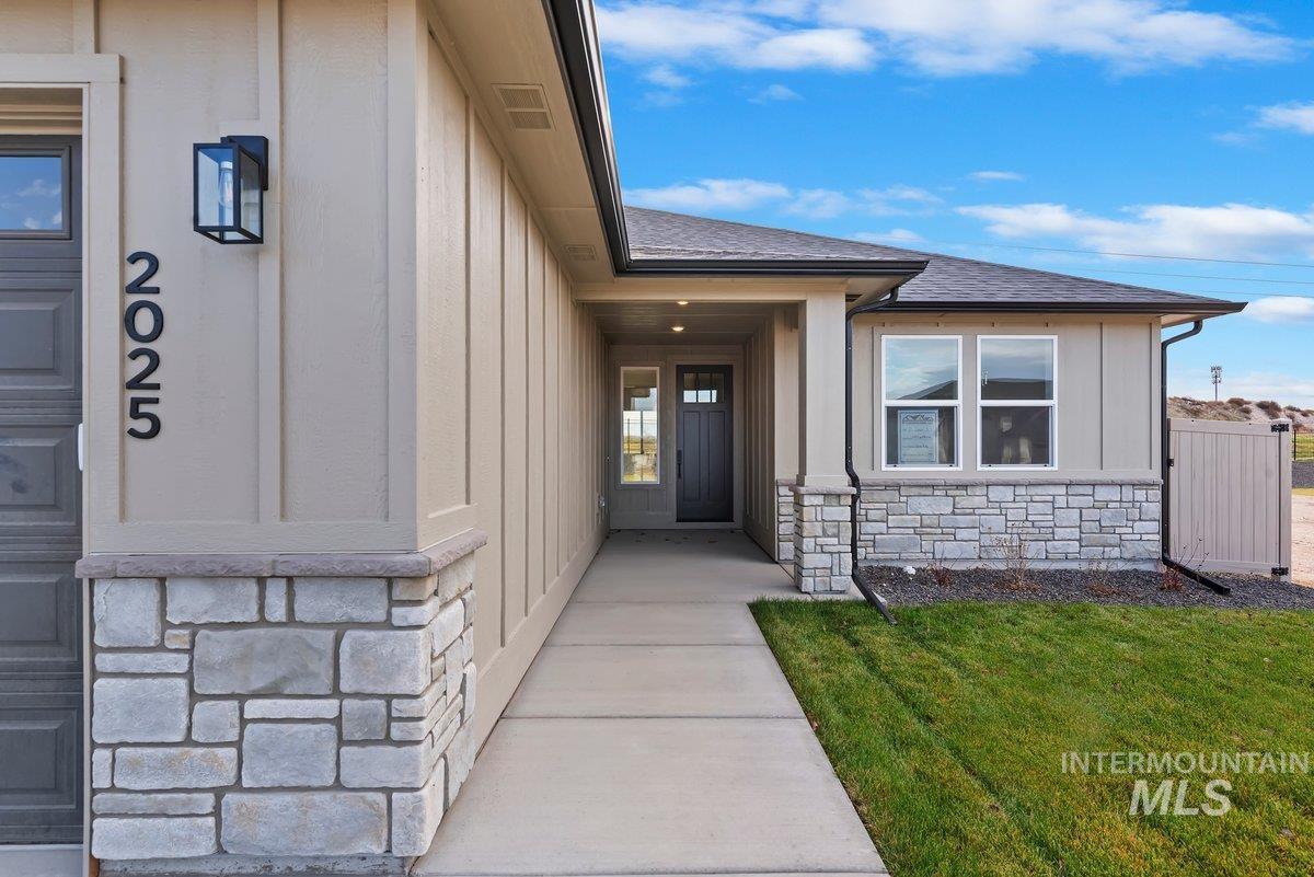 Entrance to property featuring stone siding, board and batten siding, and a shingled roof