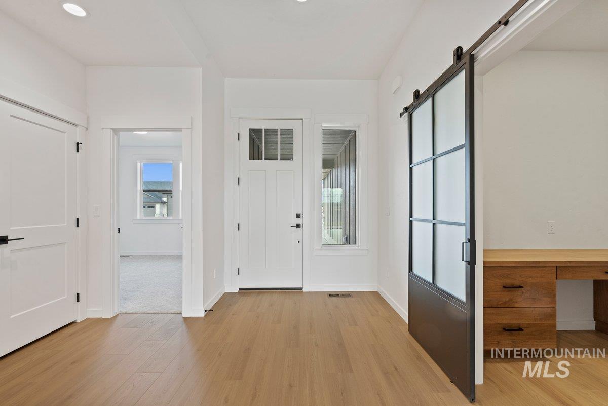 Entryway with a barn door and light wood-type flooring