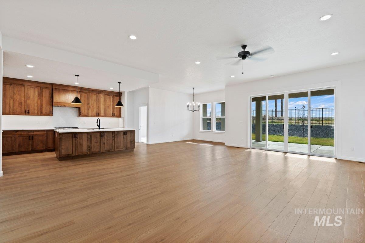 Unfurnished living room featuring recessed lighting, a ceiling fan, light wood-style floors, and a chandelier