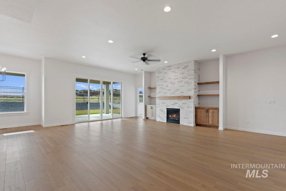 Unfurnished living room featuring light wood-style flooring, a fireplace, healthy amount of natural light, recessed lighting, and ceiling fan