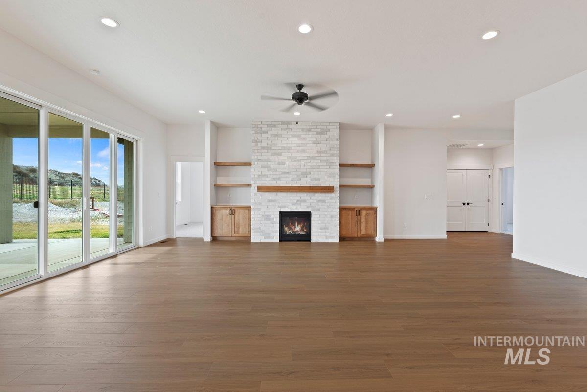 Unfurnished living room featuring recessed lighting, wood finished floors, a fireplace, and ceiling fan