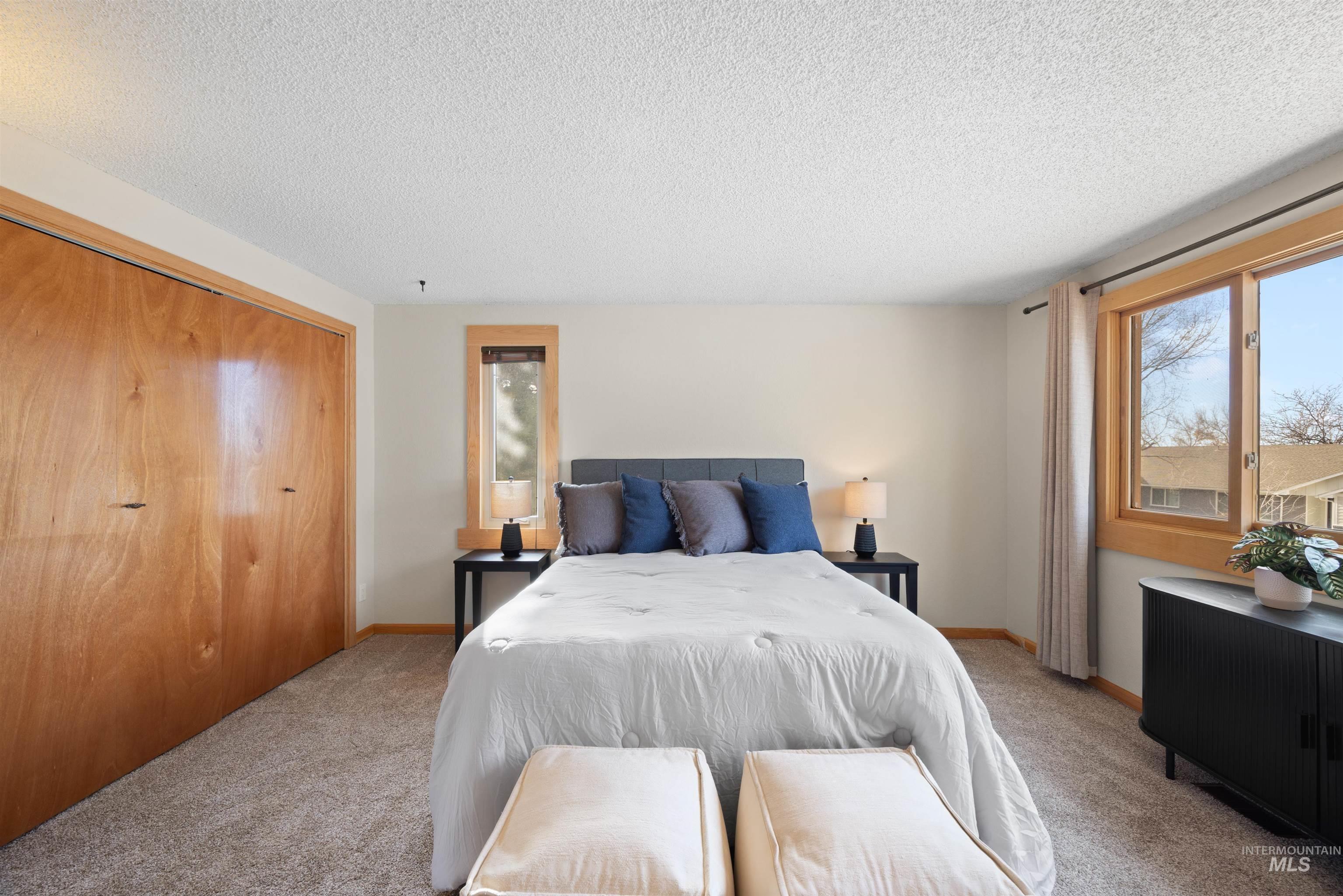 Carpeted bedroom featuring a textured ceiling, a closet, and radiator