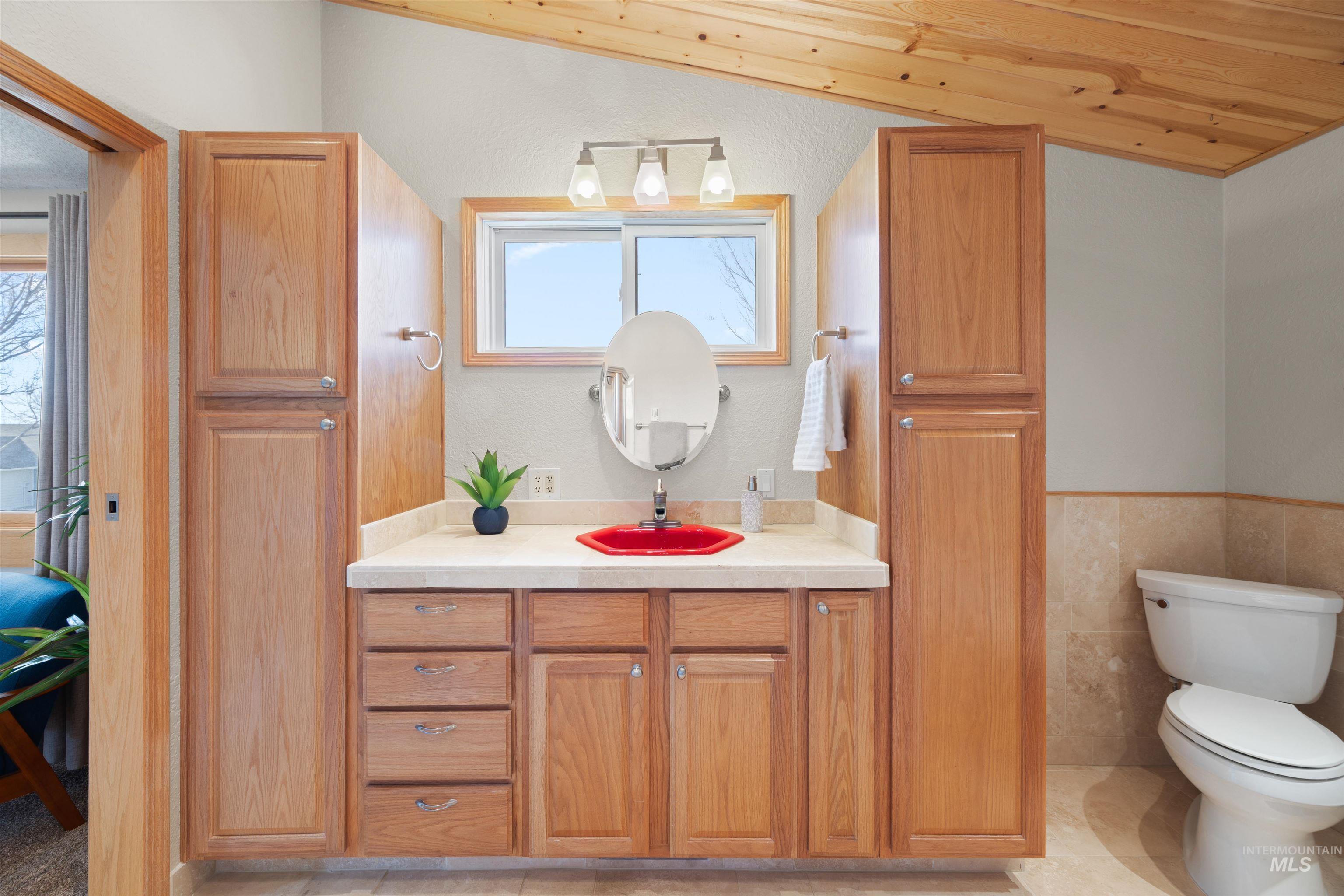 Bathroom with vanity, tile walls, a wainscoted wall, wood ceiling, and light tile patterned floors