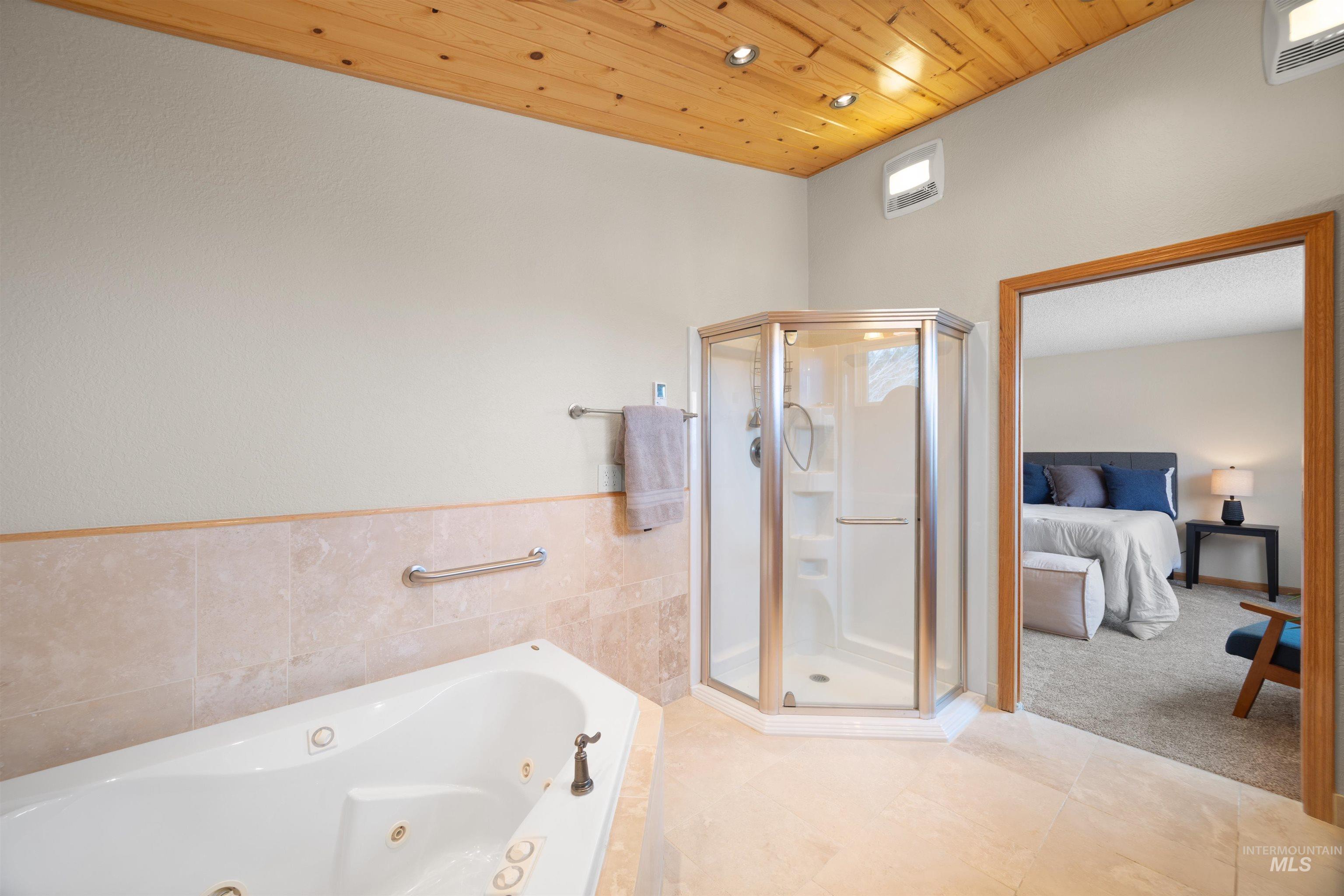Ensuite bathroom with wood ceiling, a whirlpool tub, a stall shower, light colored carpet, and recessed lighting