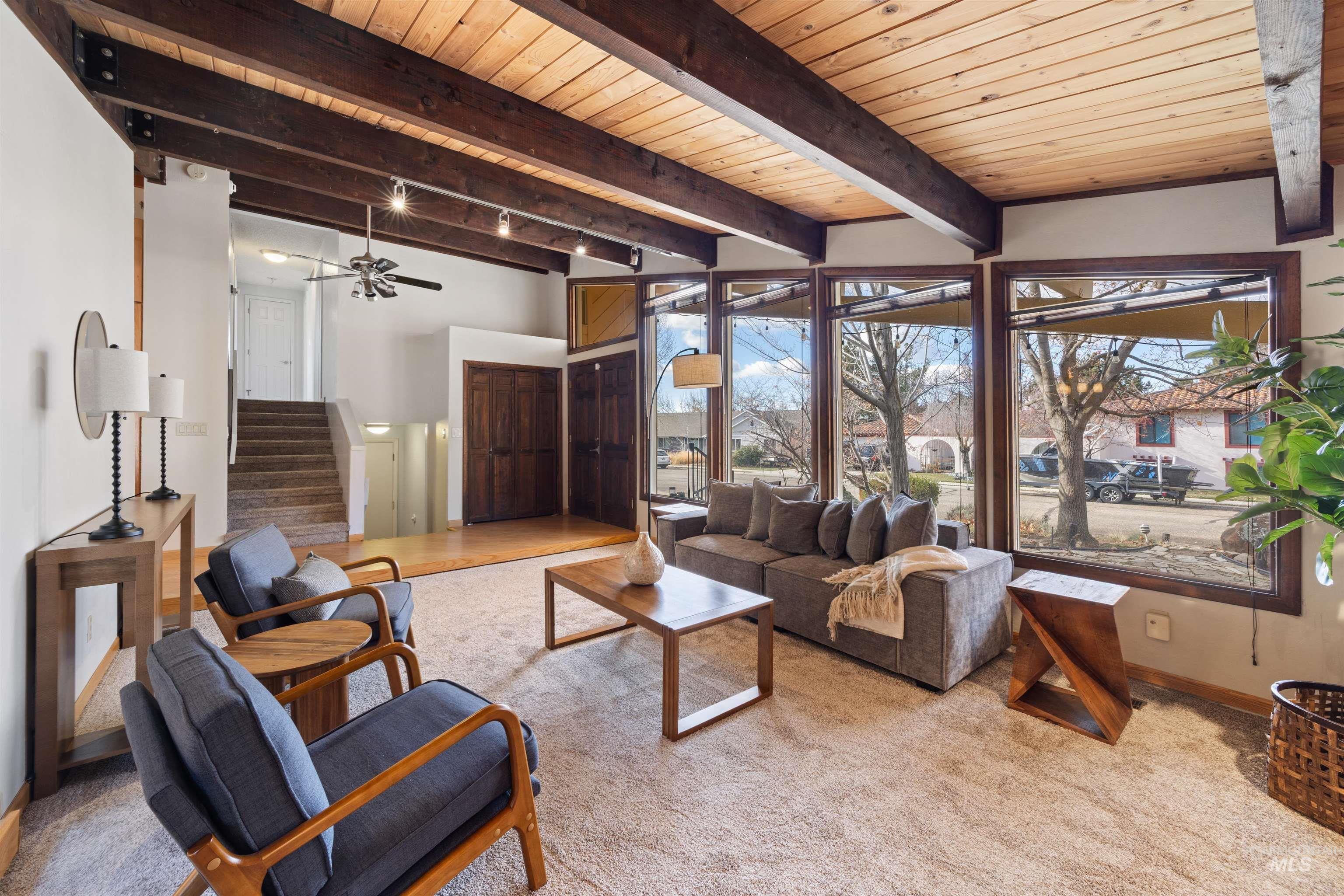 Living area featuring stairway, a wood ceiling with exposed beams, and carpet