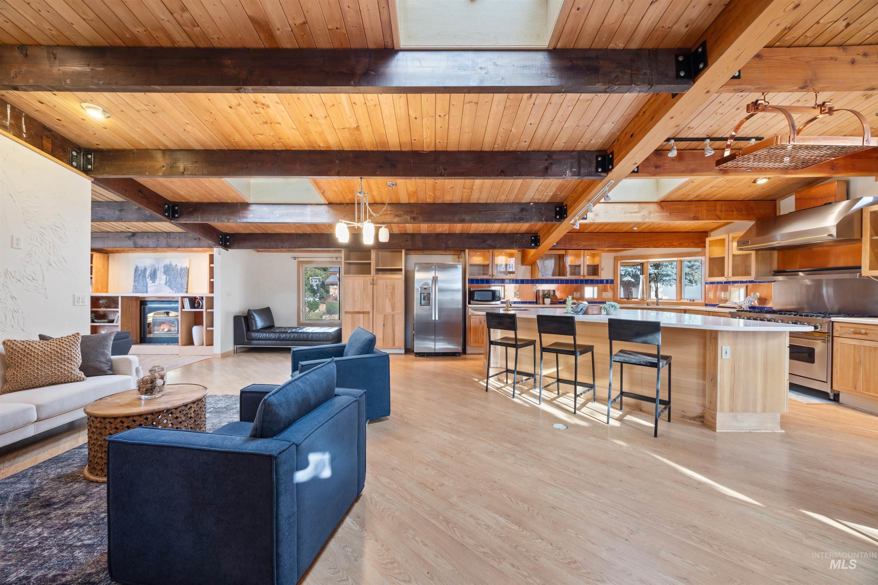 Living room featuring healthy amount of natural light, a wood ceiling with exposed beams, and light wood-type flooring