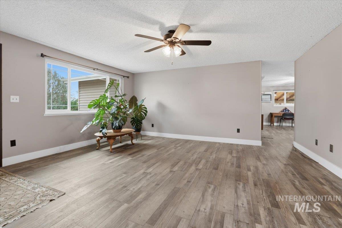 Sitting room with light wood-style floors, a textured ceiling, and ceiling fan