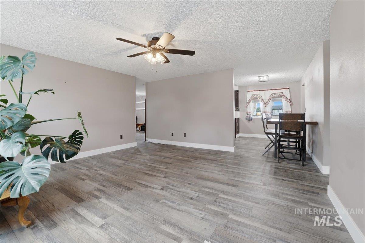 Unfurnished living room with light wood-style flooring, a textured ceiling, and a ceiling fan