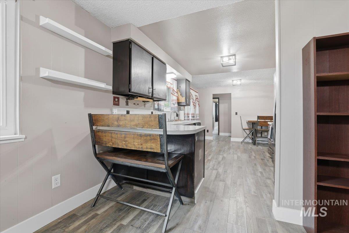 Kitchen featuring open shelves, a textured ceiling, light countertops, light wood-style flooring, and a peninsula