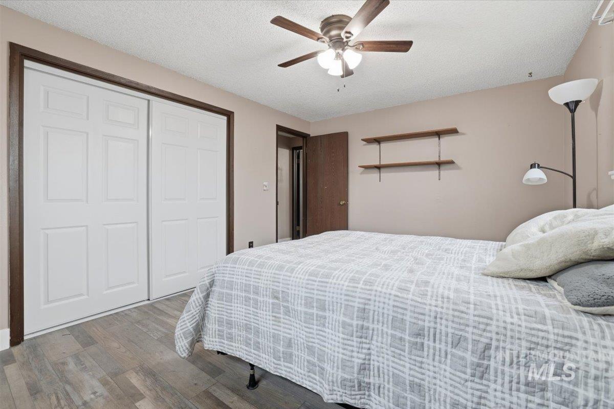 Bedroom featuring wood finished floors, ceiling fan, a textured ceiling, and a closet
