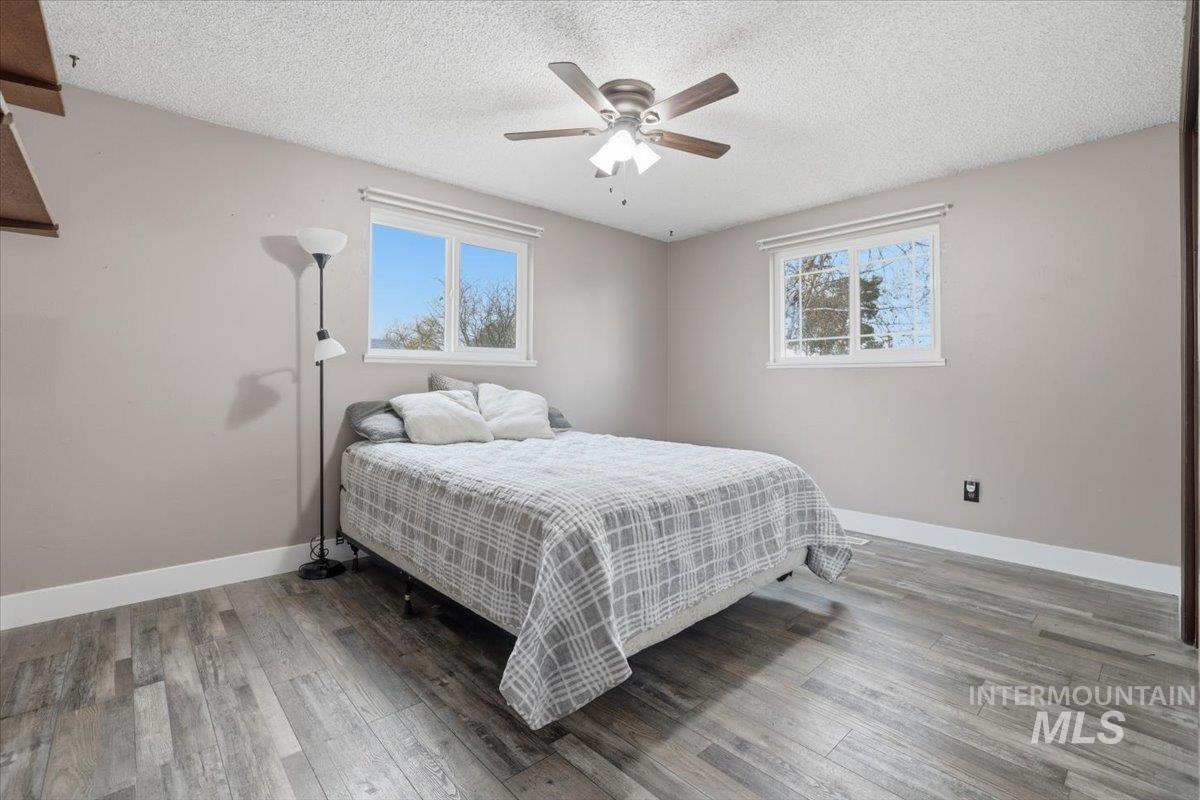 Bedroom with a ceiling fan, light wood-type flooring, and a textured ceiling