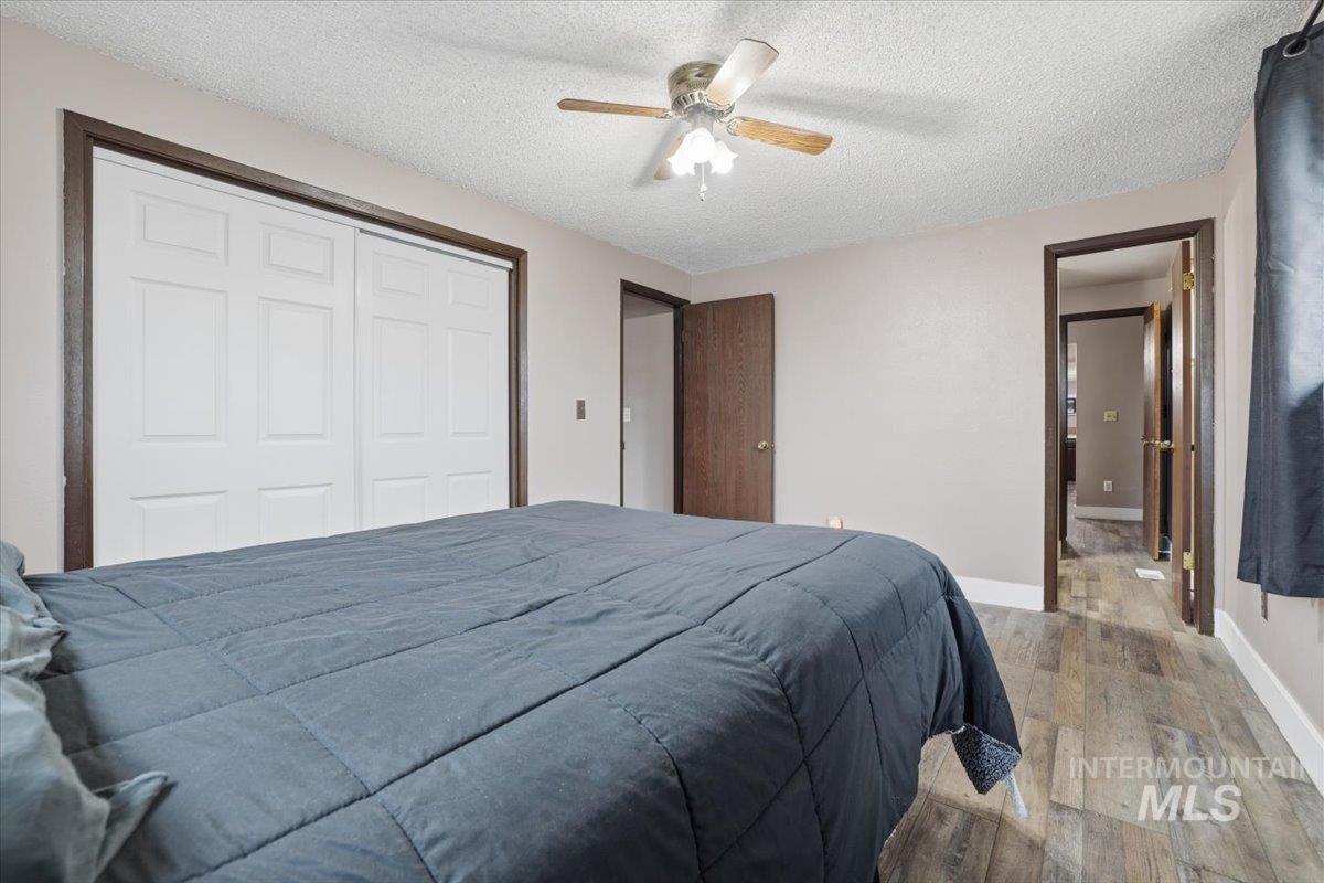 Bedroom with hardwood / wood-style flooring, a textured ceiling, ceiling fan, and a closet