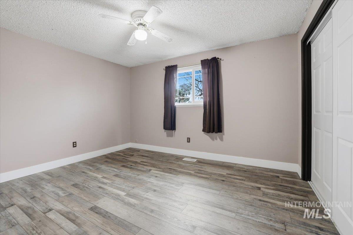 Unfurnished bedroom featuring light wood-style floors, a textured ceiling, a closet, and ceiling fan