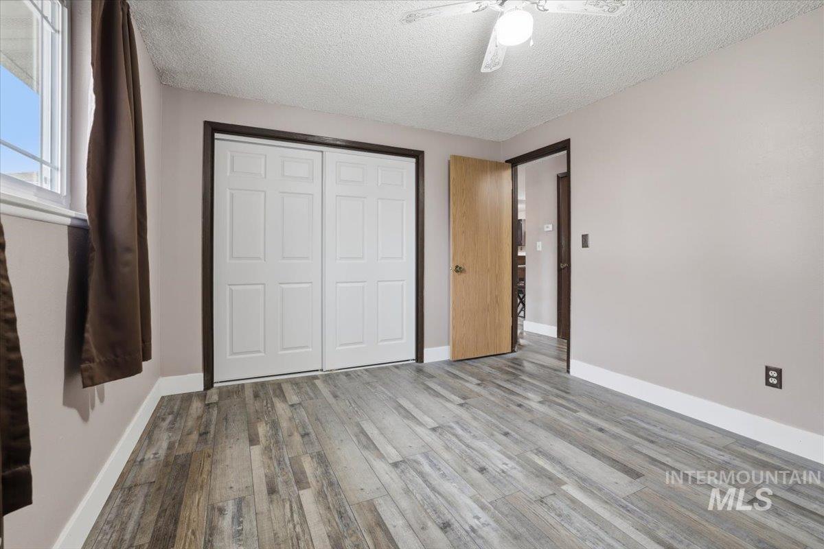Unfurnished bedroom with a textured ceiling, light wood-type flooring, ceiling fan, and a closet