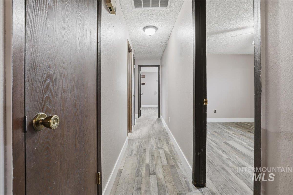 Hallway with light wood-style flooring and a textured ceiling