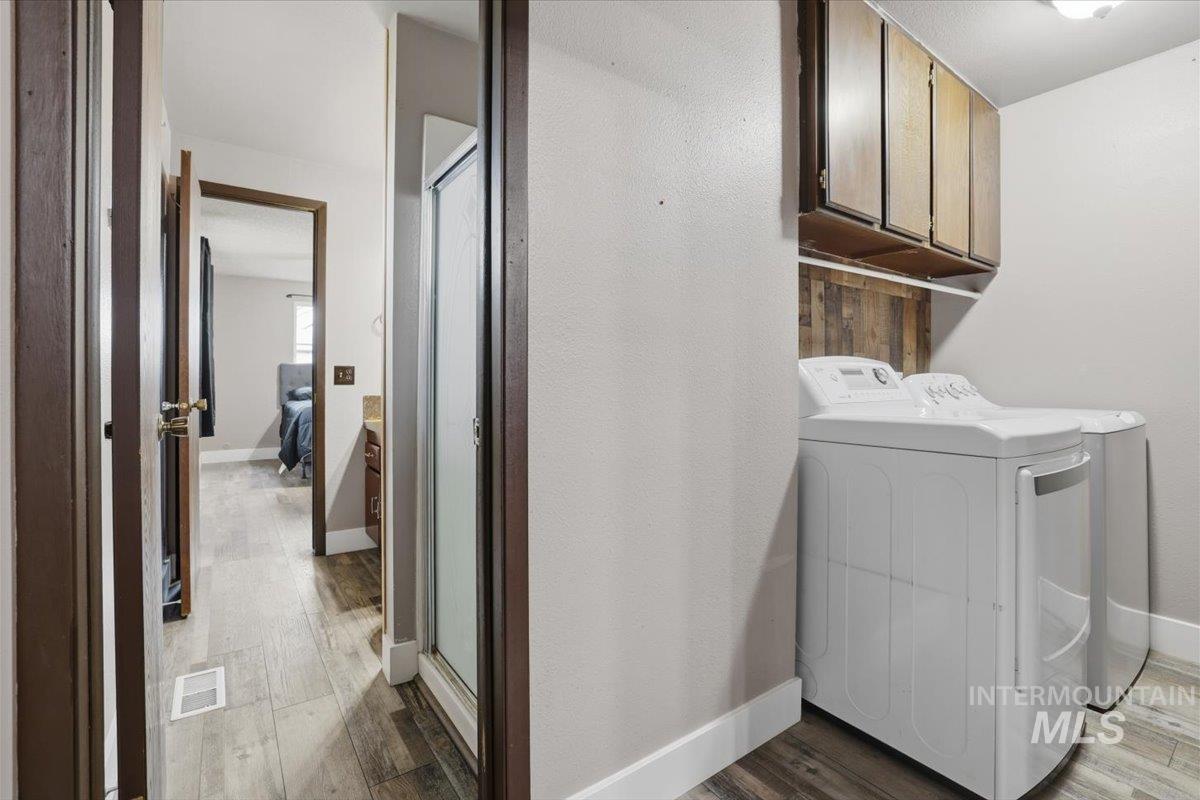 Laundry area with washer and dryer, dark wood-style floors, and cabinet space