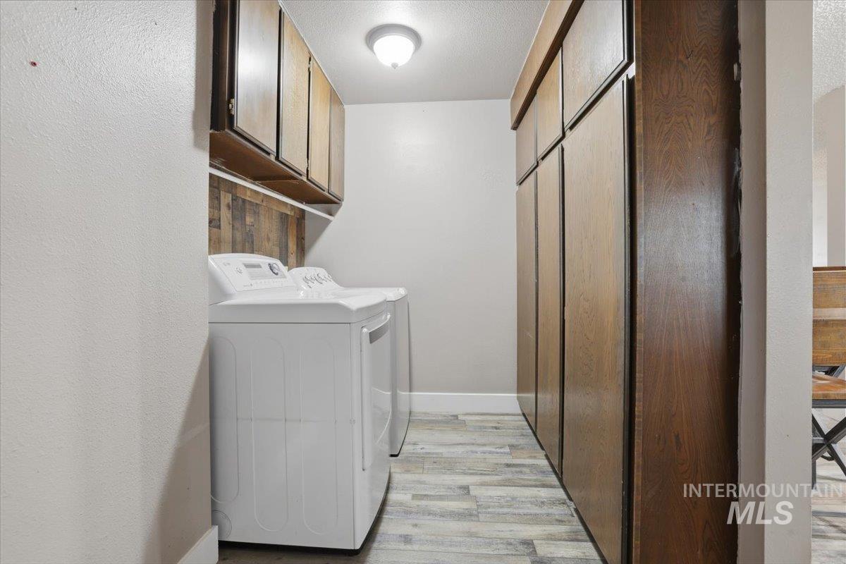 Washroom featuring light wood-style floors, washing machine and dryer, and cabinet space
