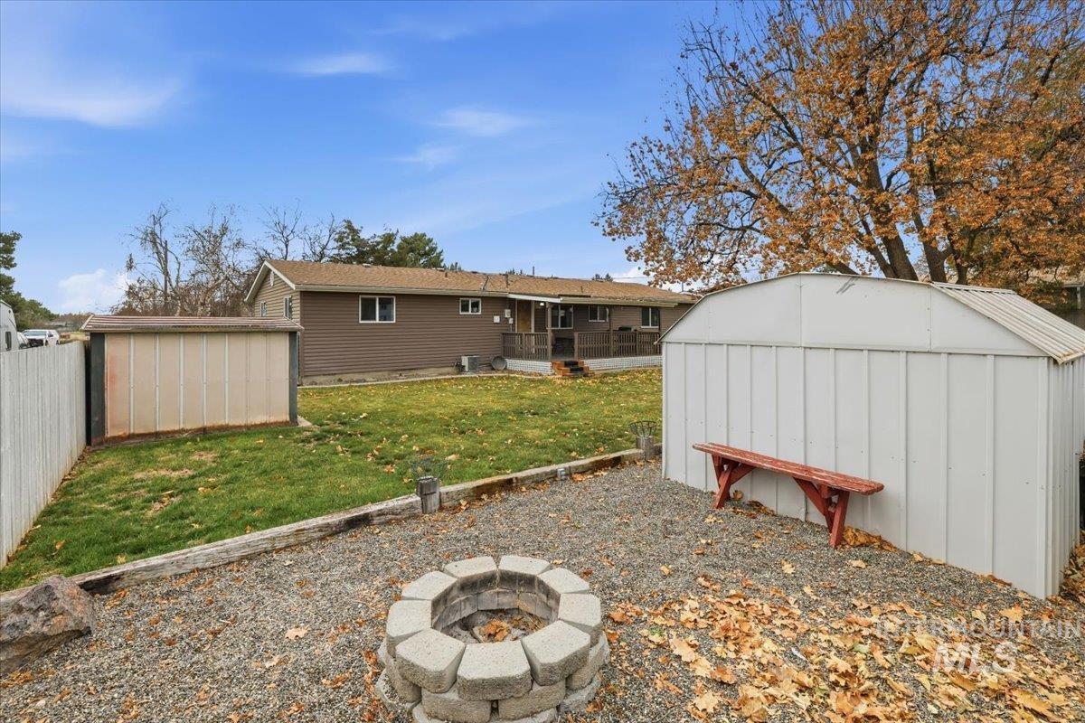 Rear view of house with a storage shed, a fenced backyard, an outdoor fire pit, and a sunroom