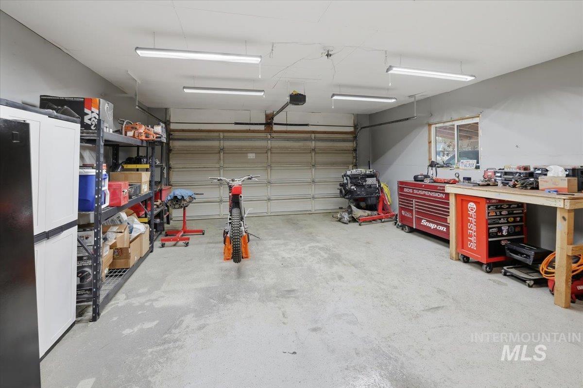Garage featuring a workshop area and black fridge