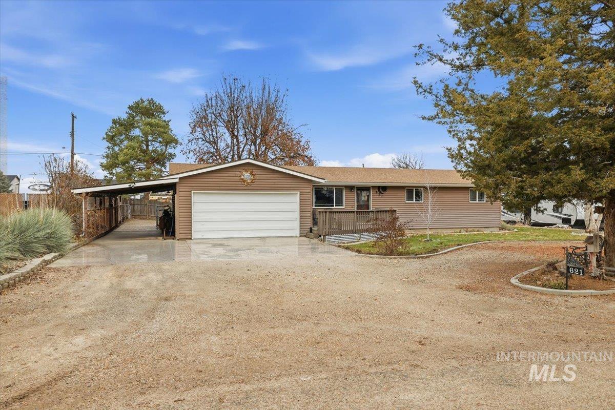 View of front of property featuring dirt driveway, an attached carport, and an attached garage