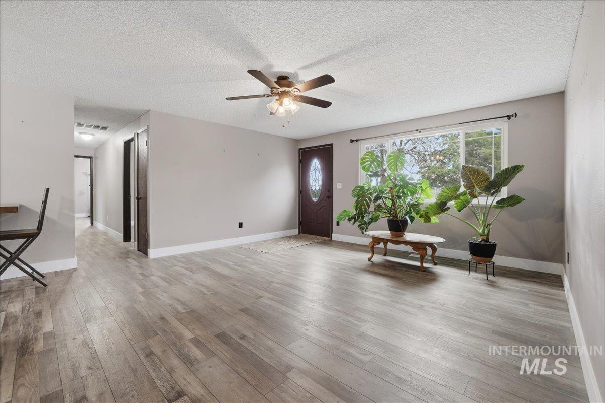 Foyer entrance with a textured ceiling, a ceiling fan, and light wood-type flooring