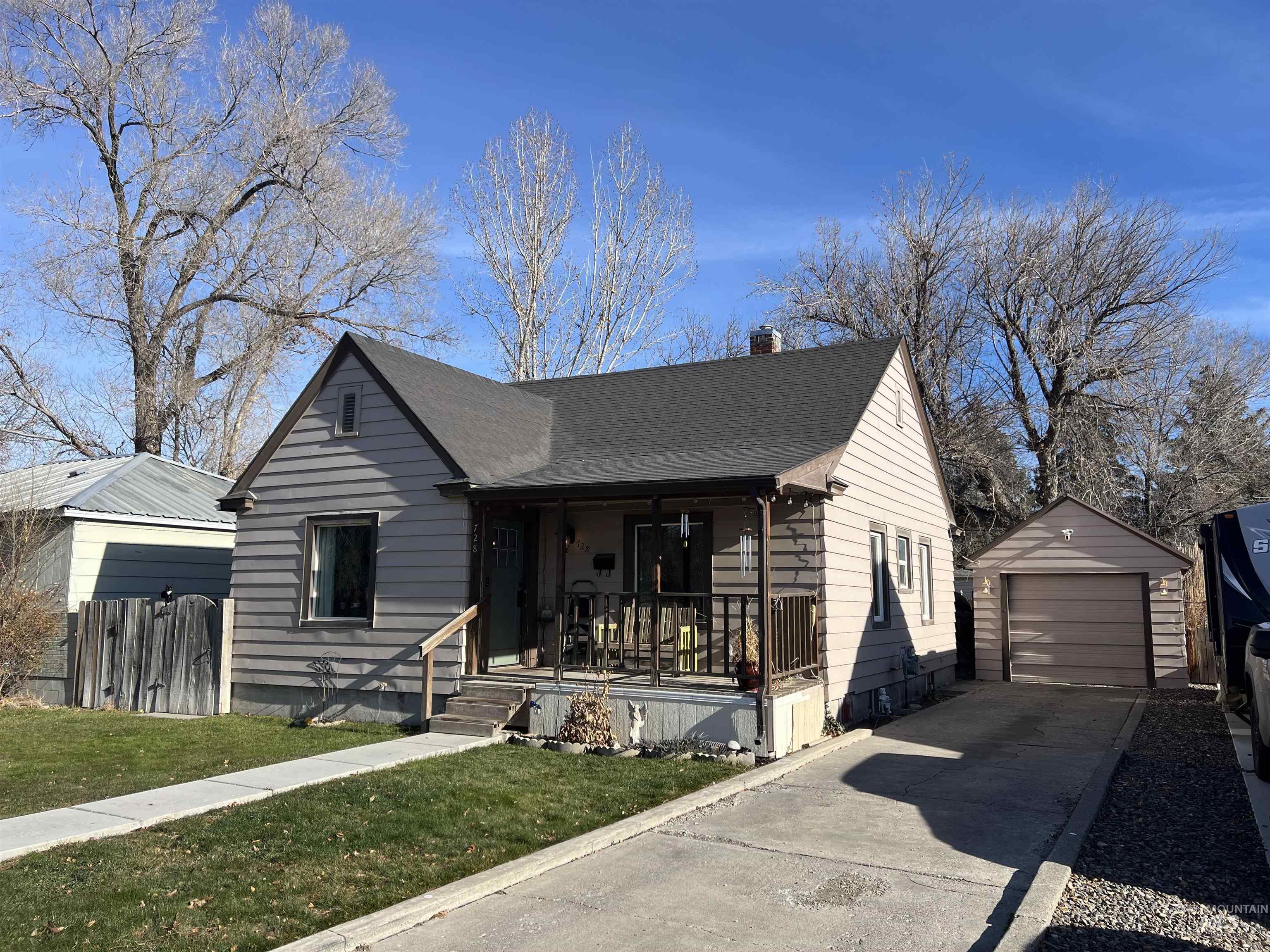 Bungalow with a porch, an outdoor structure, a chimney, concrete driveway, and a garage