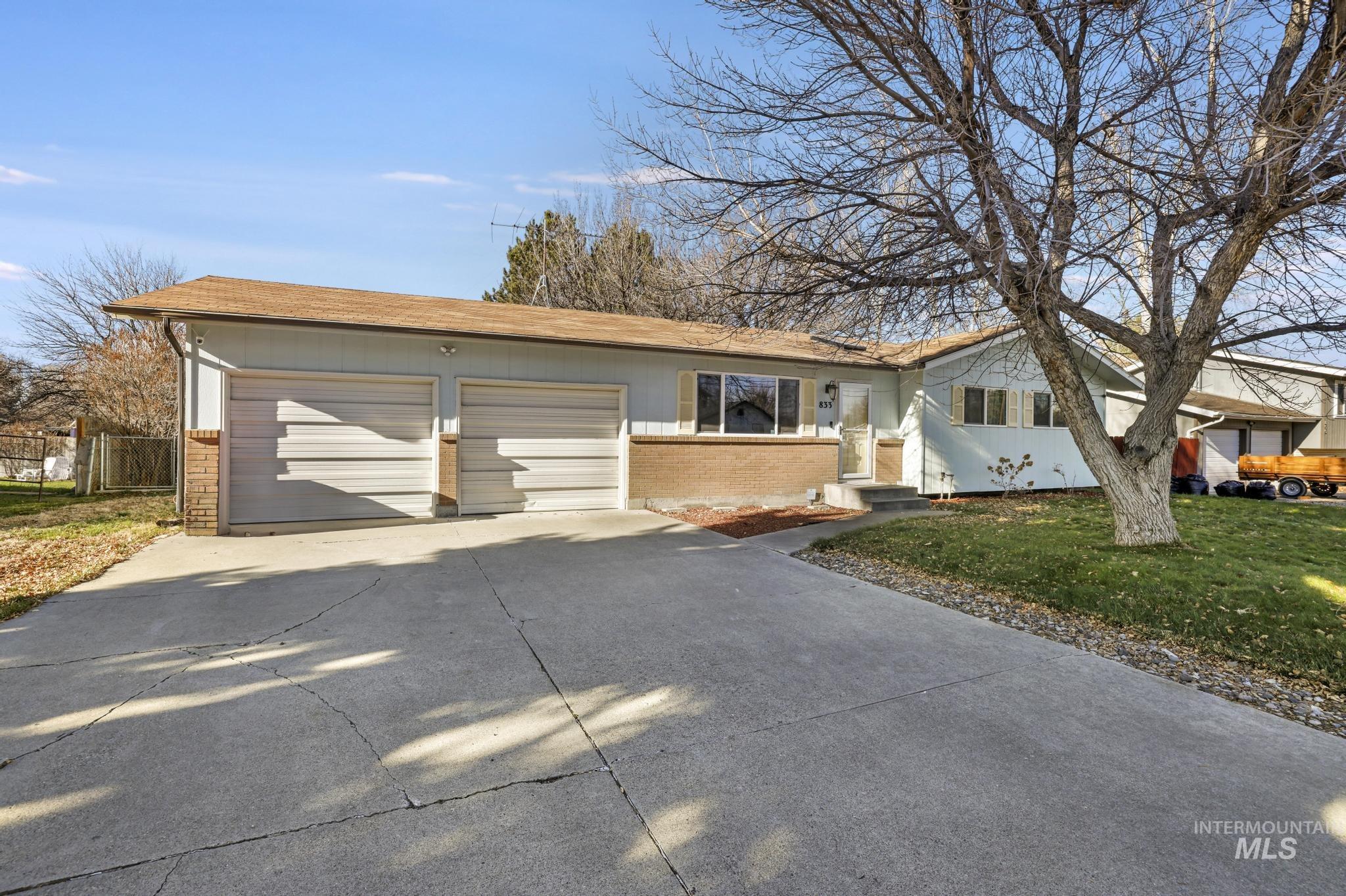 Ranch-style house featuring brick siding, driveway, a front yard, a garage, and roof with shingles