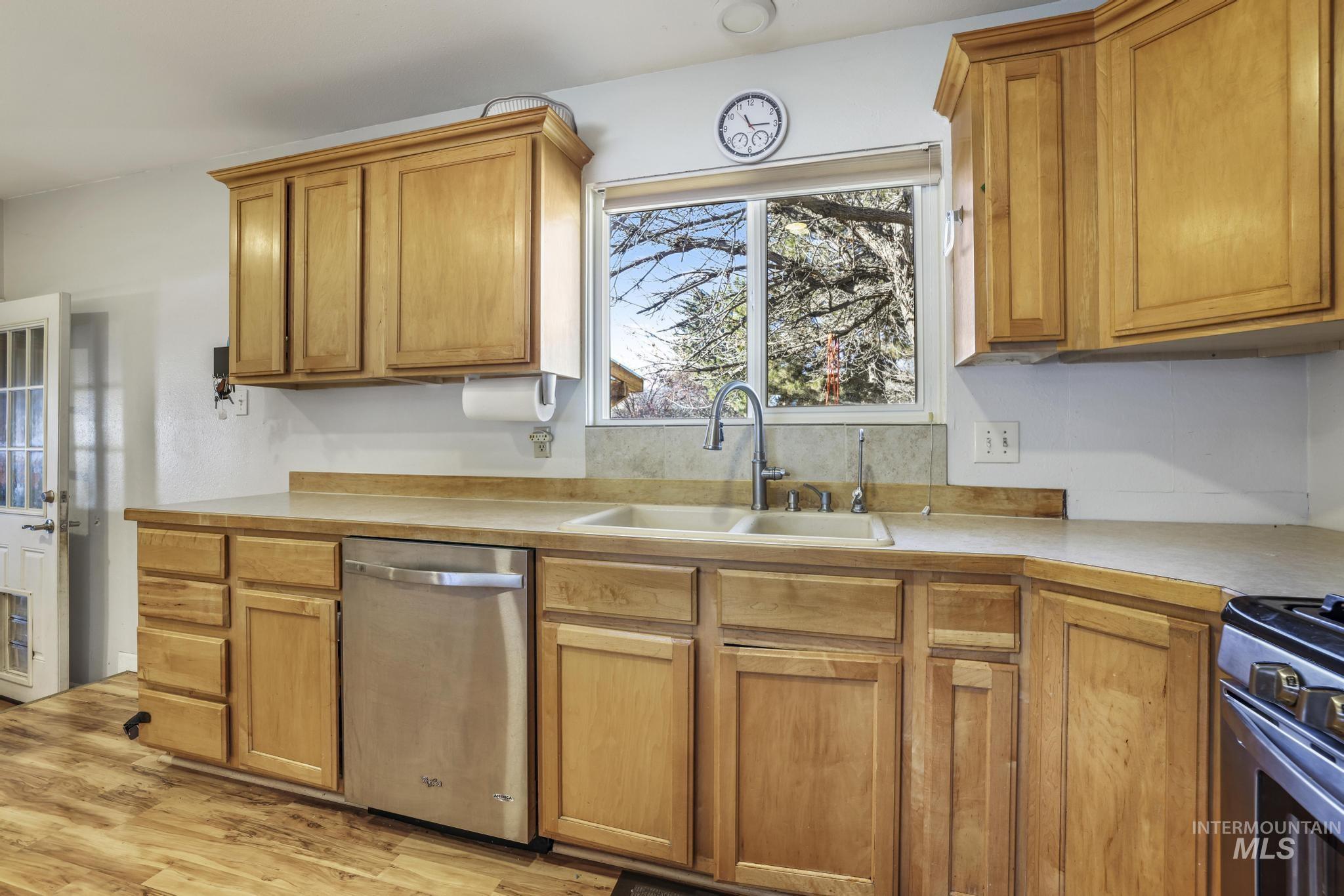Kitchen with light countertops, appliances with stainless steel finishes, brown cabinets, and light wood finished floors