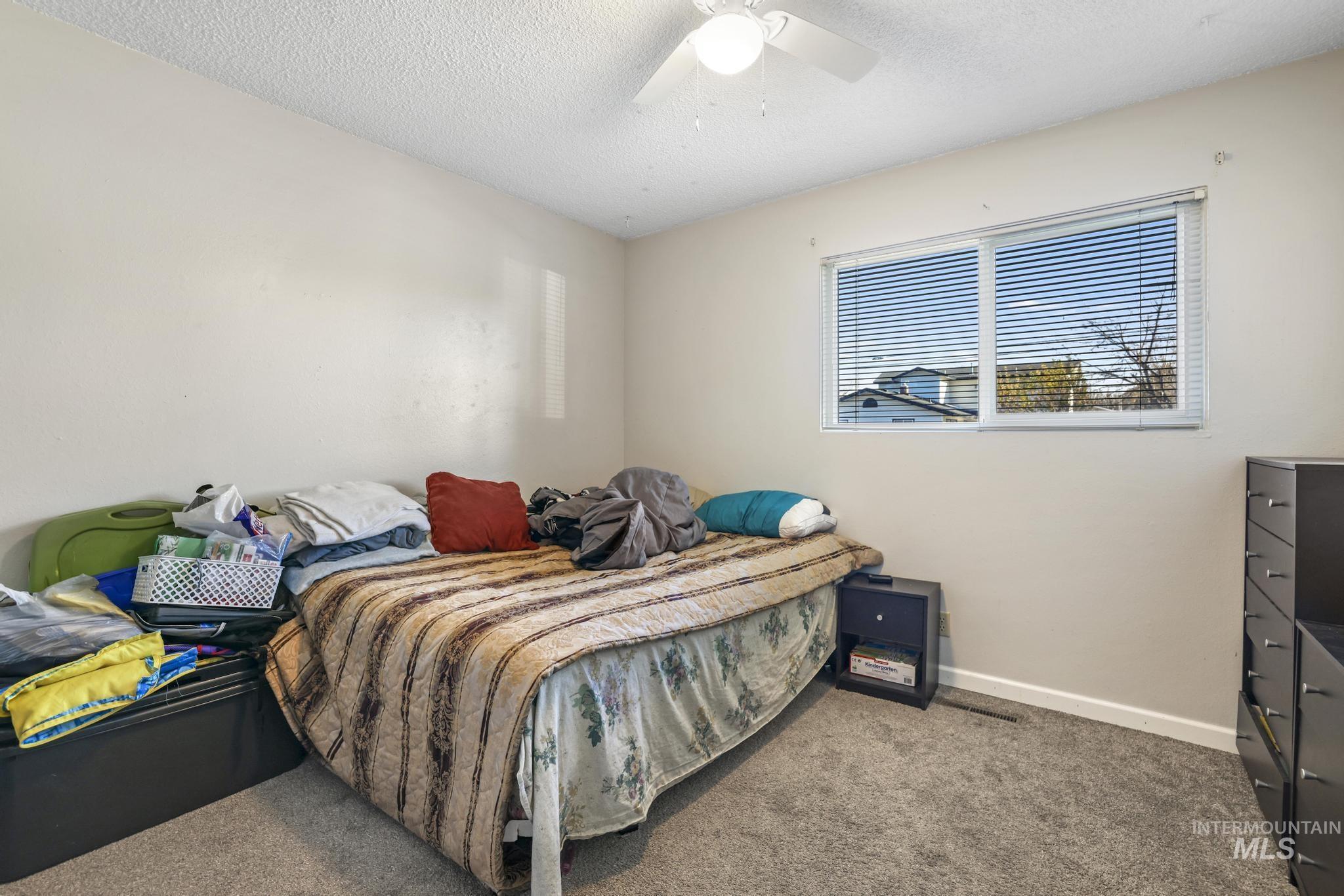 Carpeted bedroom featuring a textured ceiling and ceiling fan