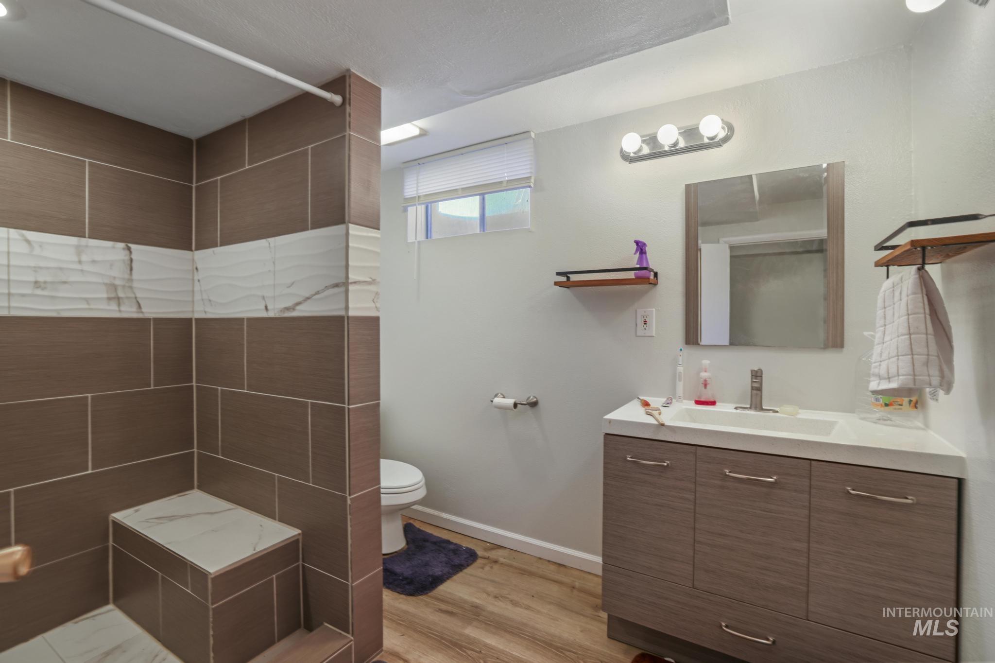 Bathroom with vanity, light wood-style floors, and a tile shower
