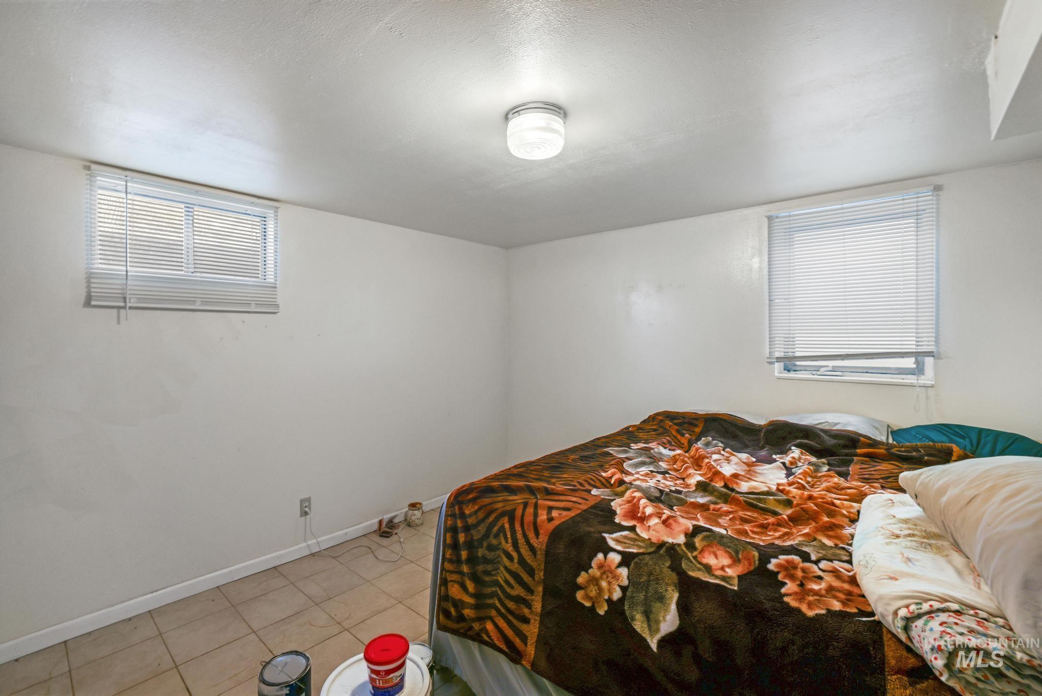 Tiled bedroom featuring a textured ceiling and baseboards