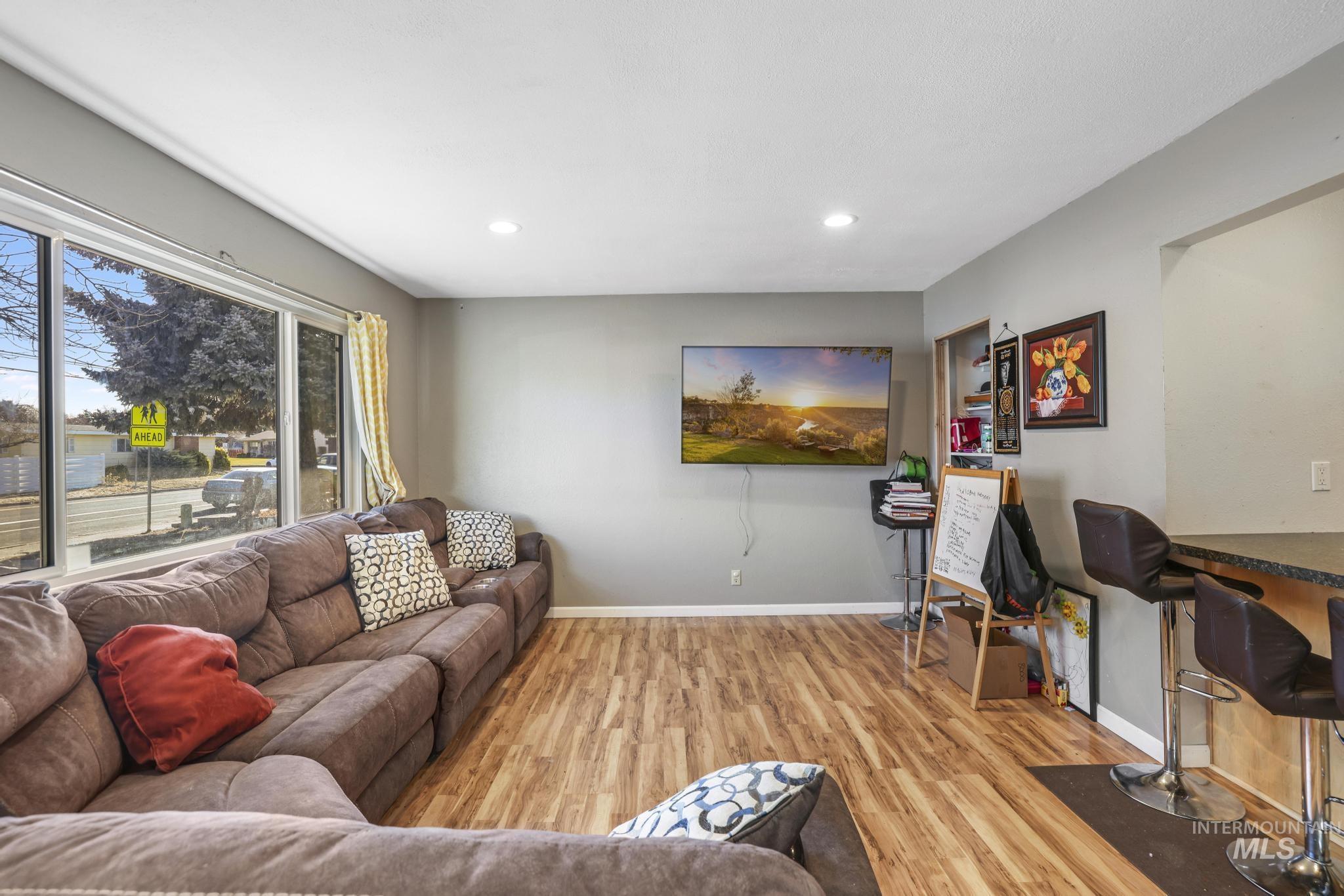 Living area with light wood finished floors and recessed lighting