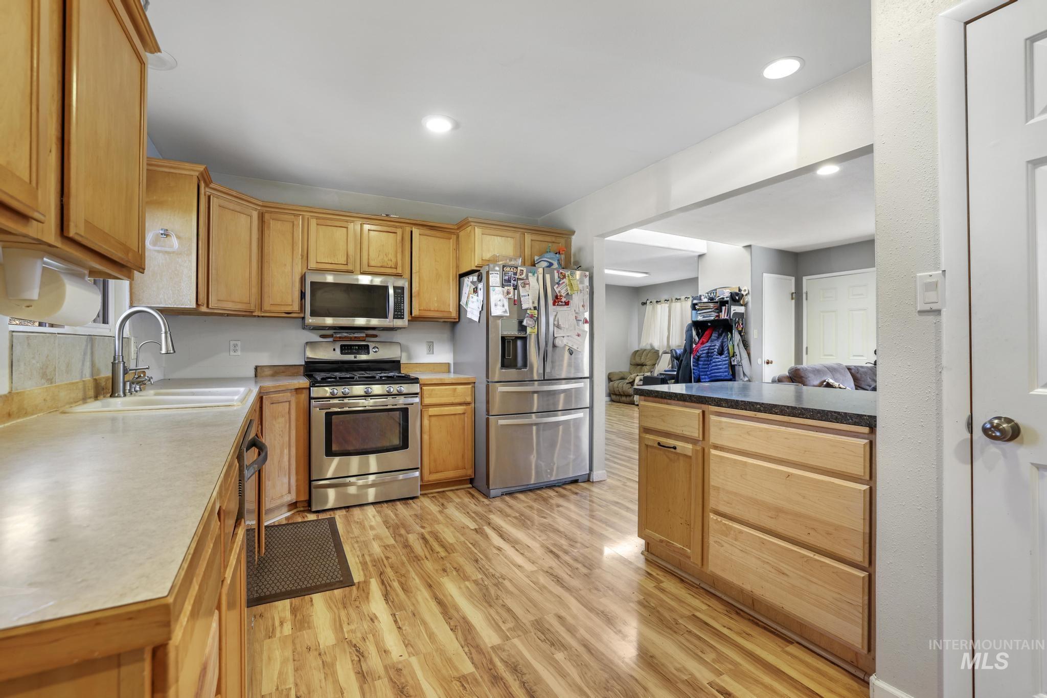 Kitchen featuring stainless steel appliances, light wood-style flooring, recessed lighting, and open floor plan