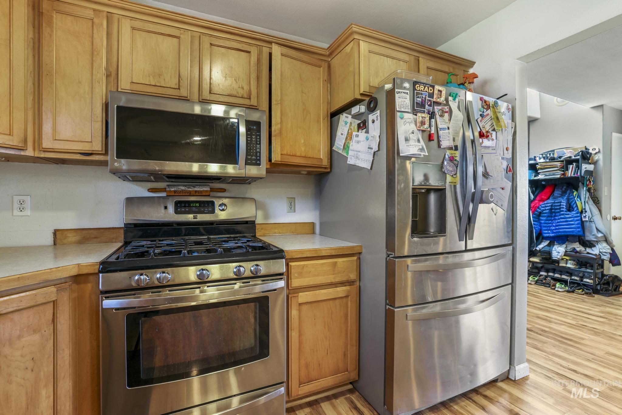 Kitchen featuring stainless steel appliances, light countertops, light wood-style flooring, and brown cabinetry