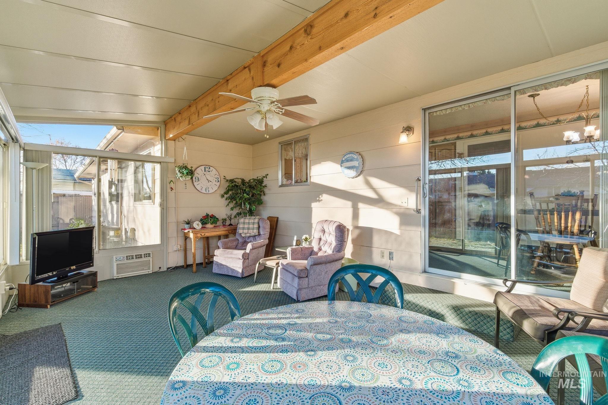 Sunroom / solarium featuring outdoor dining area, beamed ceiling, ceiling fan, and an outdoor living space