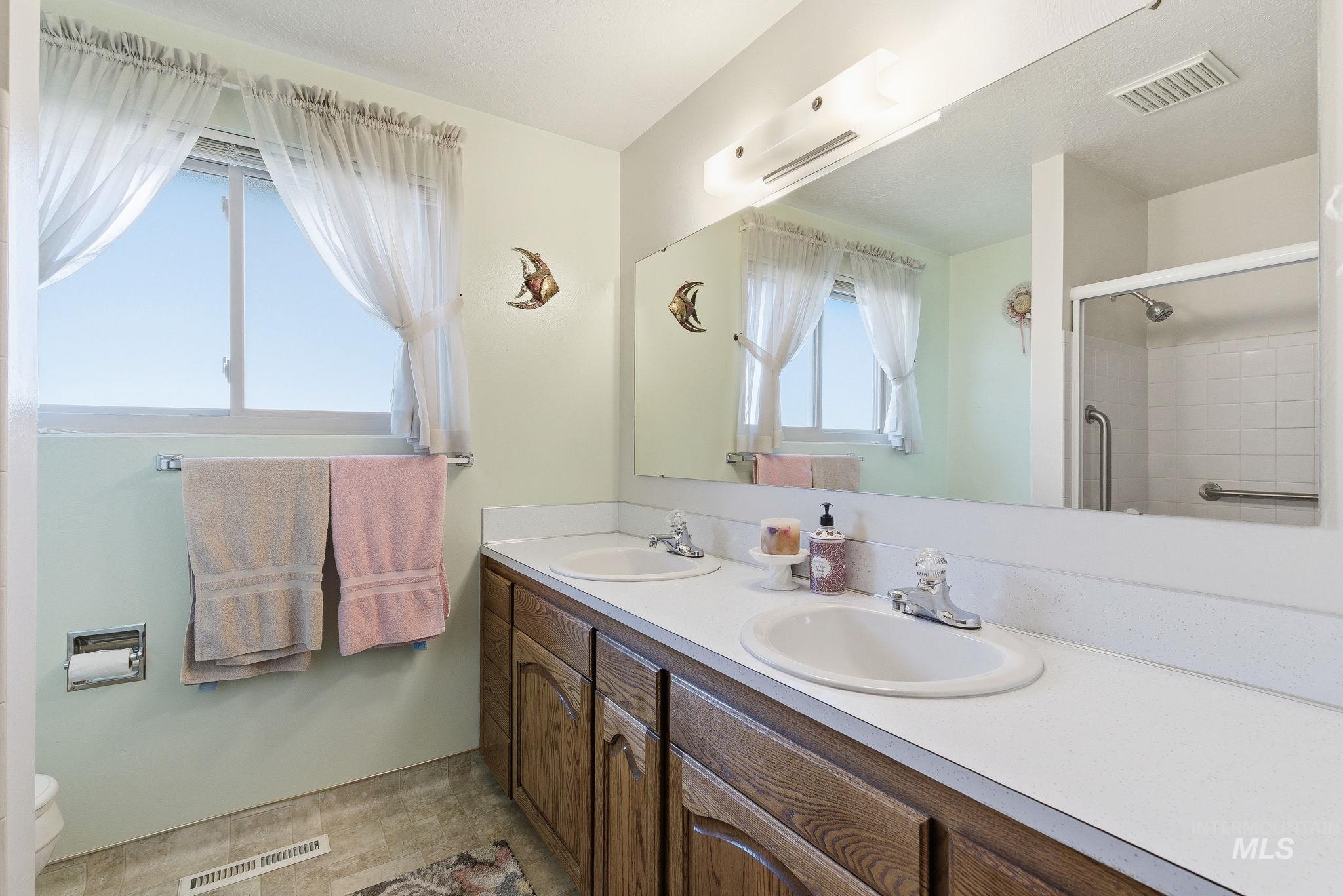 Full bathroom featuring double vanity and a shower
