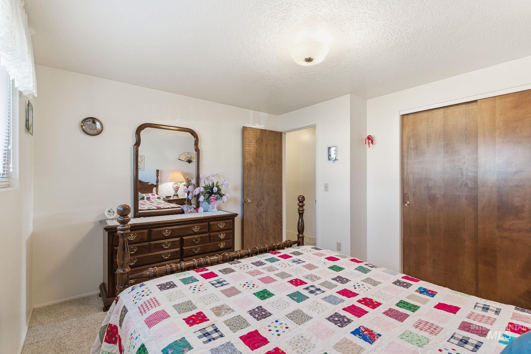 Bedroom featuring a closet, a textured ceiling, and light colored carpet
