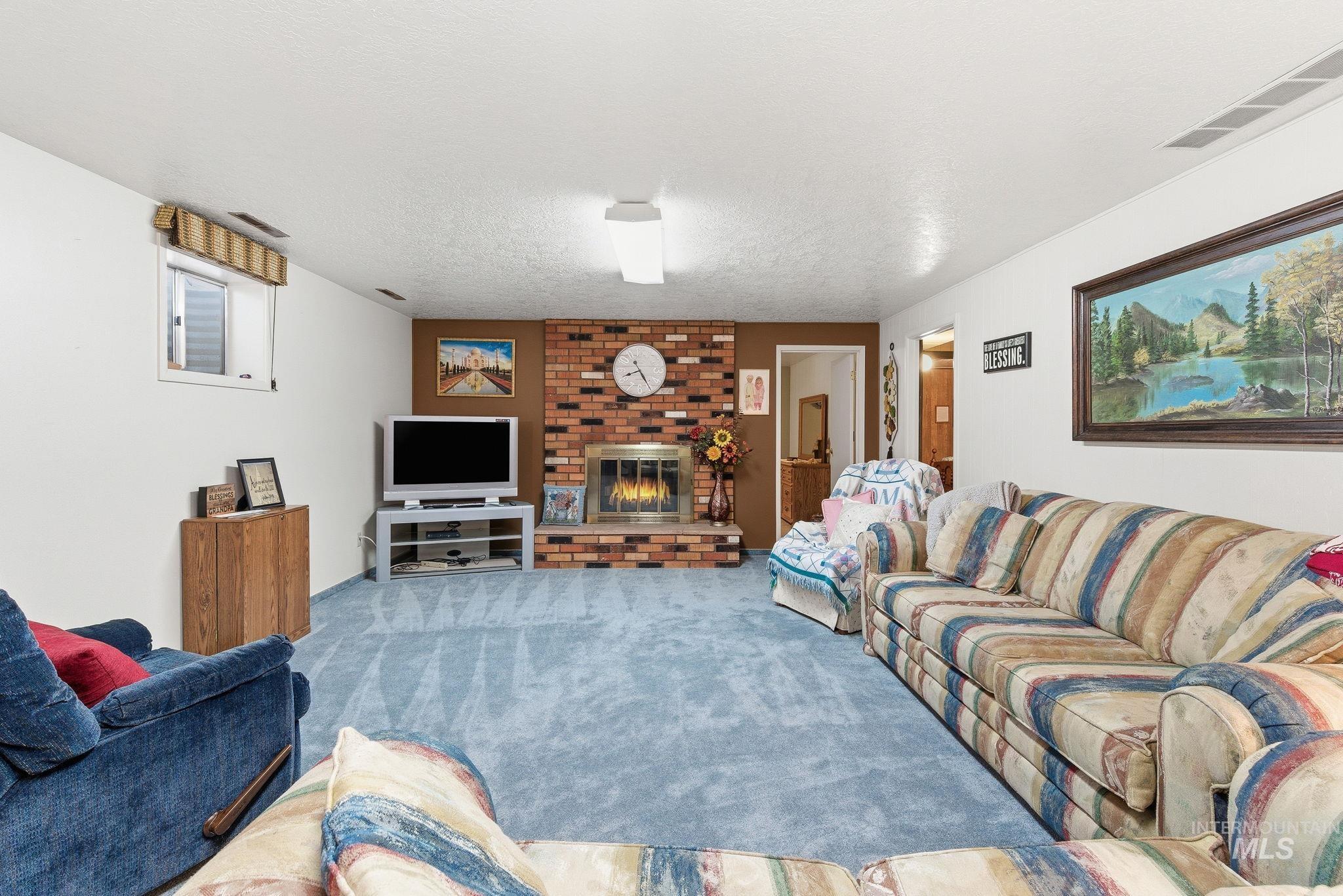 Living room with a fireplace, carpet flooring, and a textured ceiling