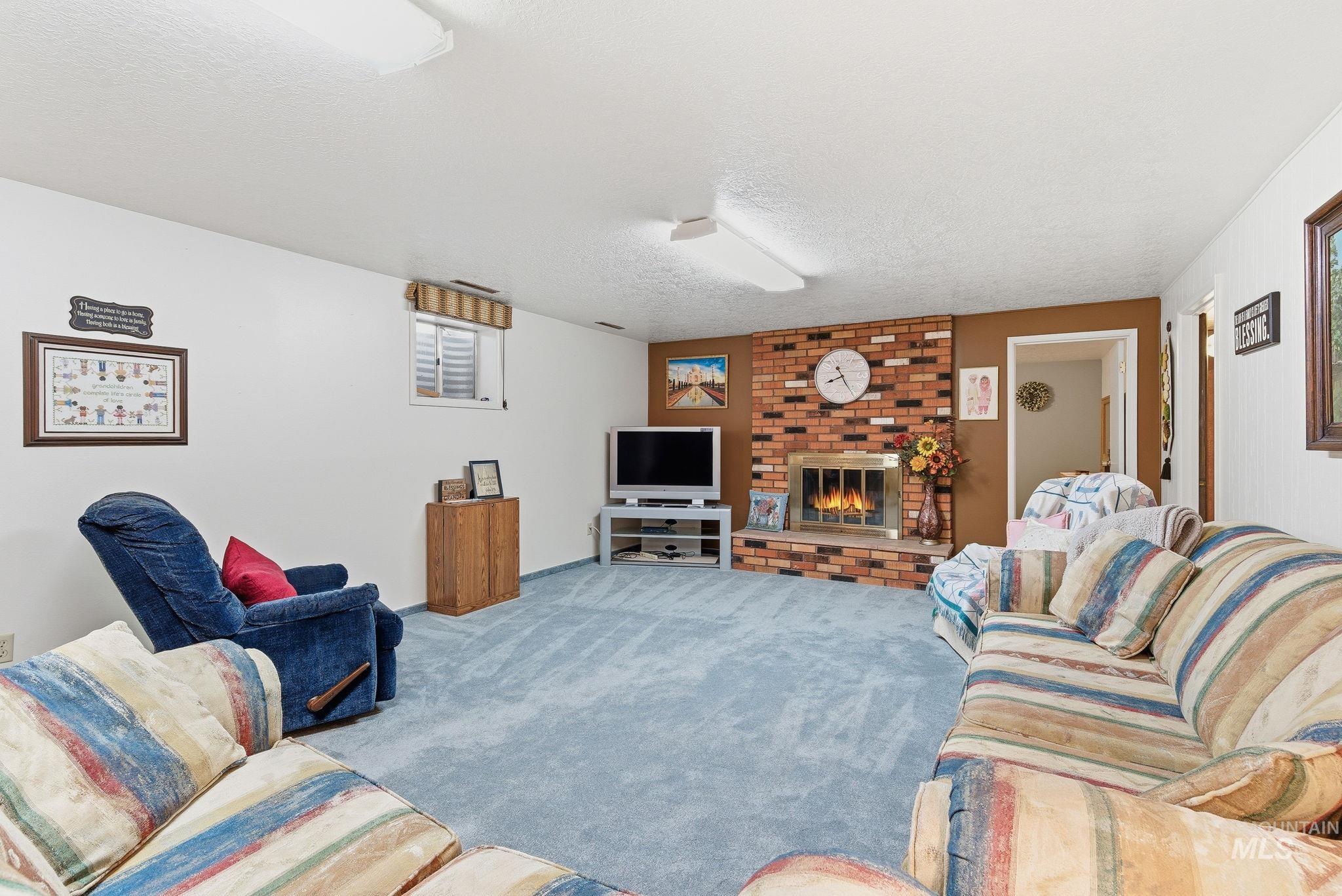 Living room featuring a fireplace, carpet flooring, and a textured ceiling