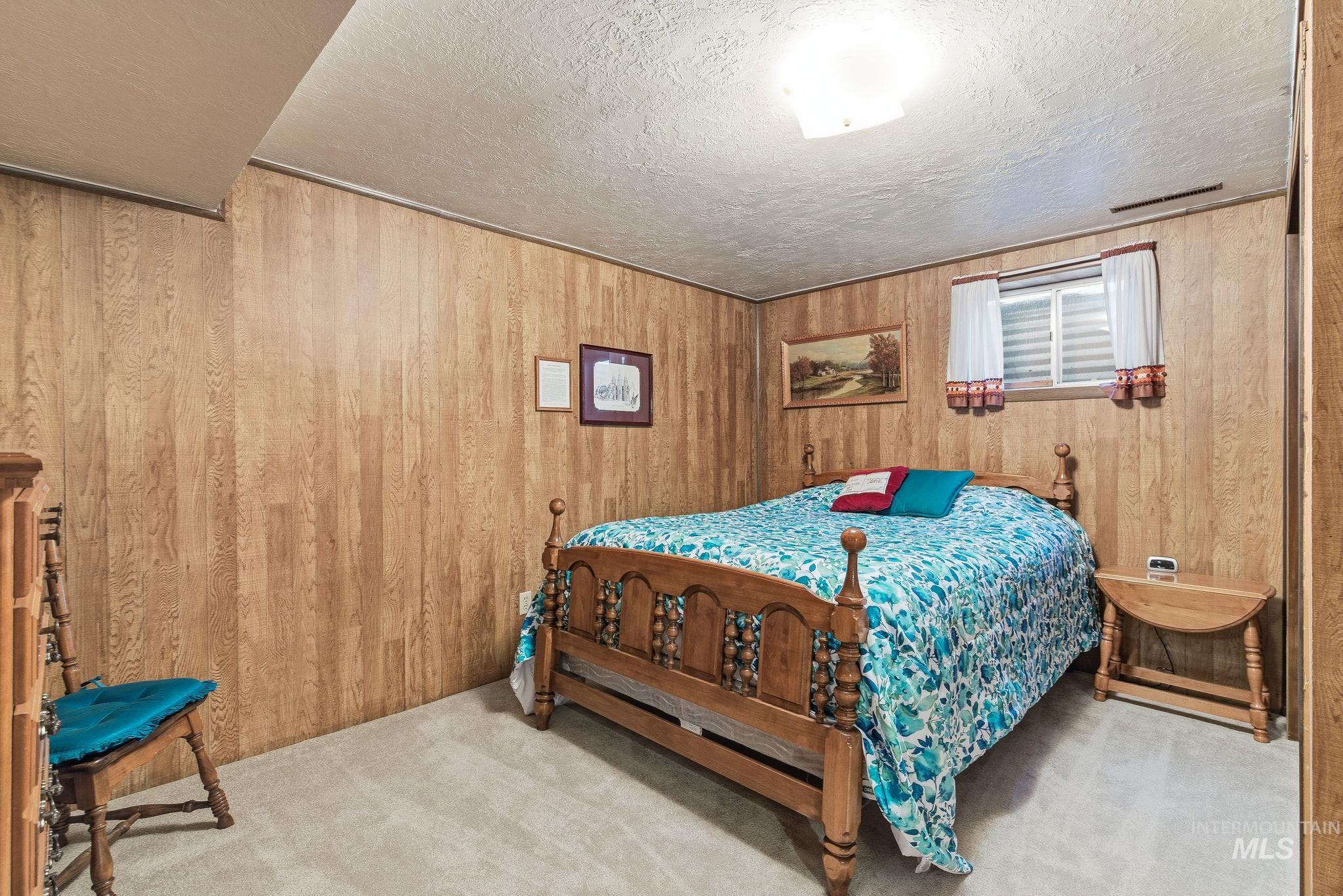 Carpeted bedroom with wood walls and a textured ceiling