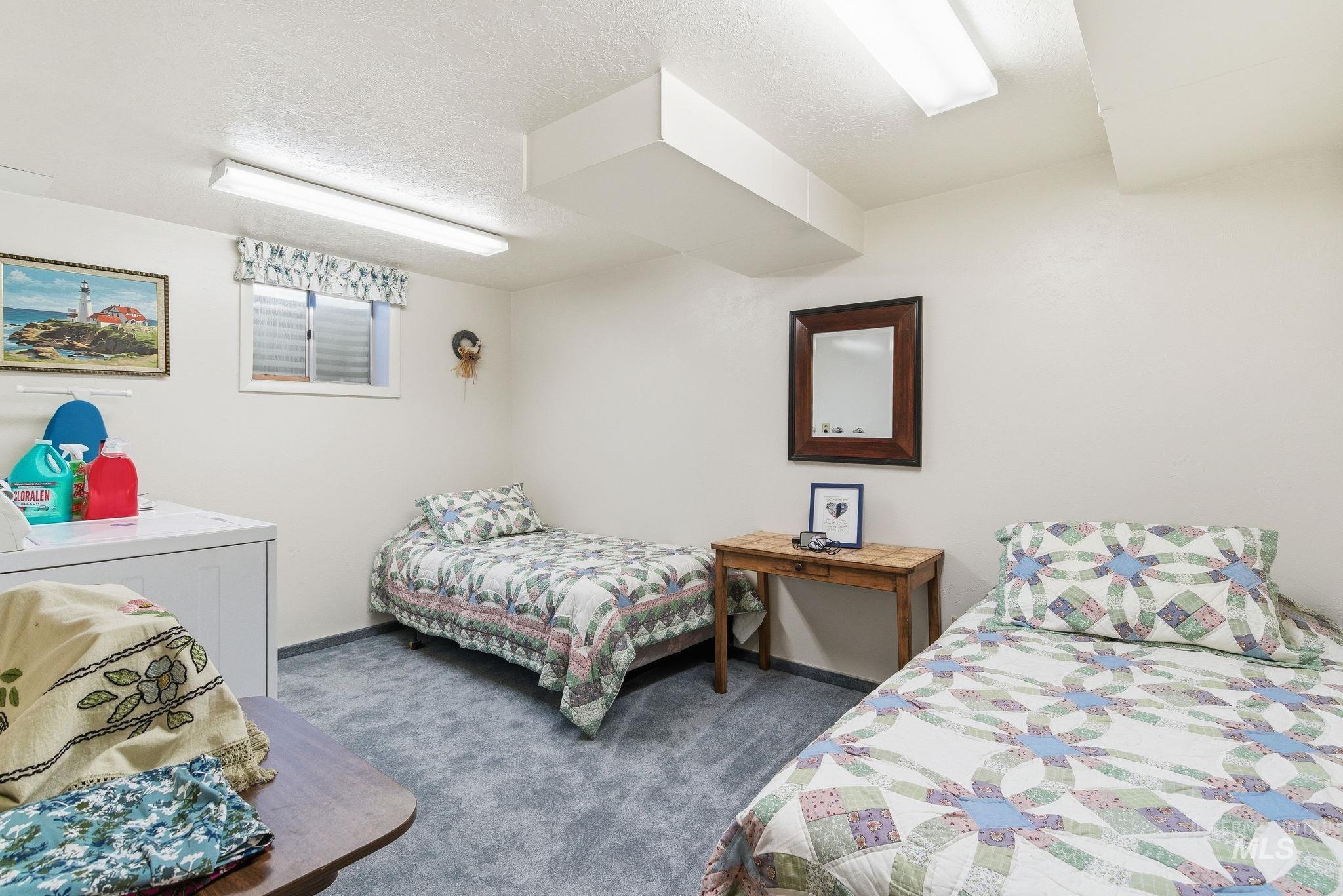 Bedroom with dark carpet, separate washer and dryer, and a textured ceiling