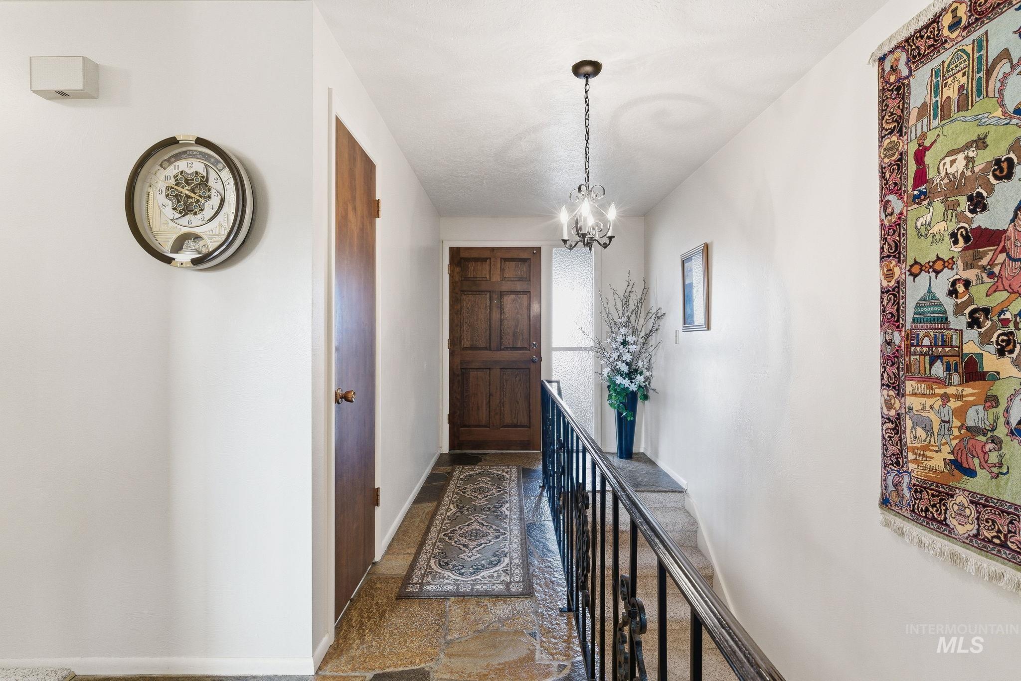 Entryway featuring stone tile floors and a chandelier