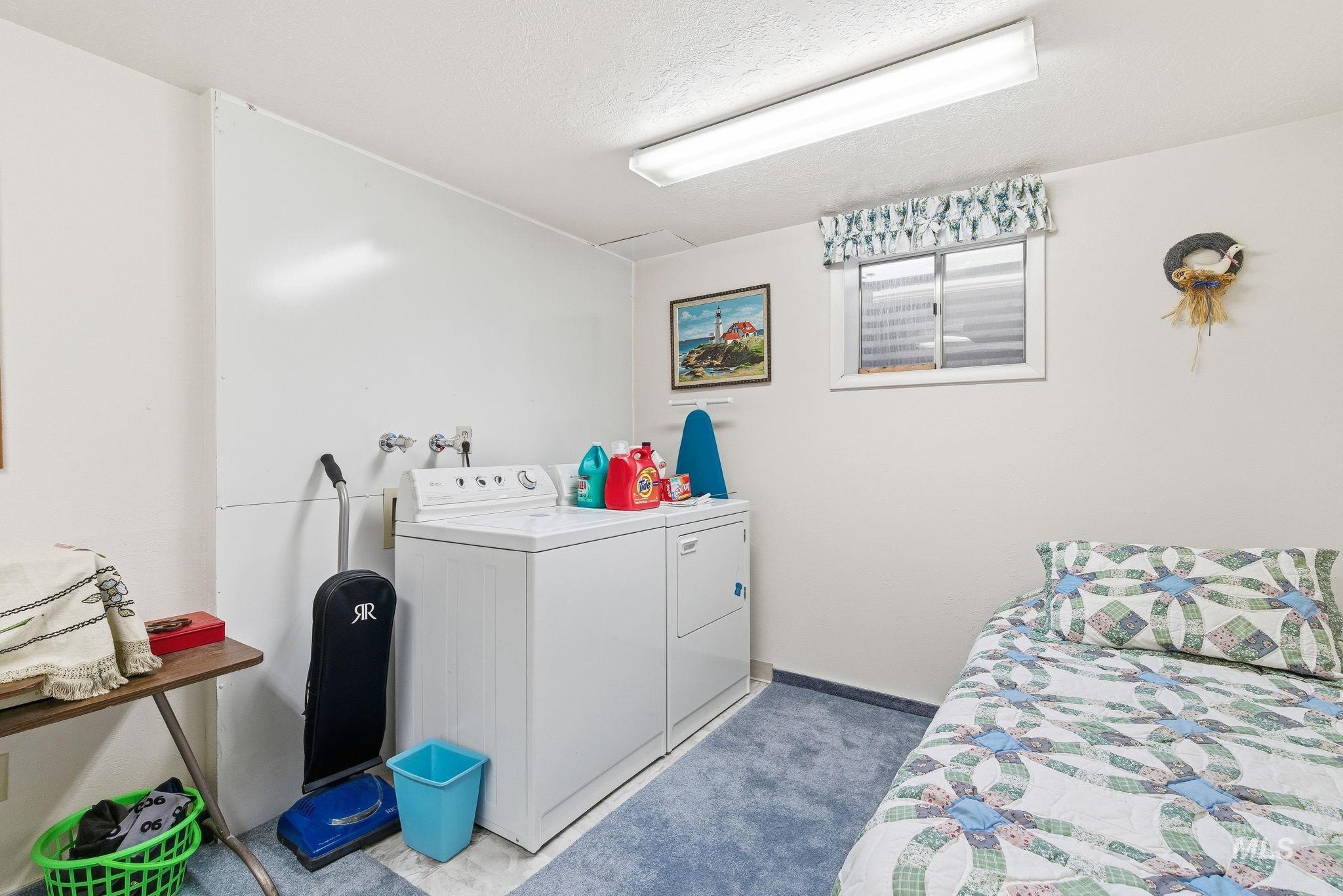 Laundry room with a textured ceiling, washer and dryer, and carpet flooring