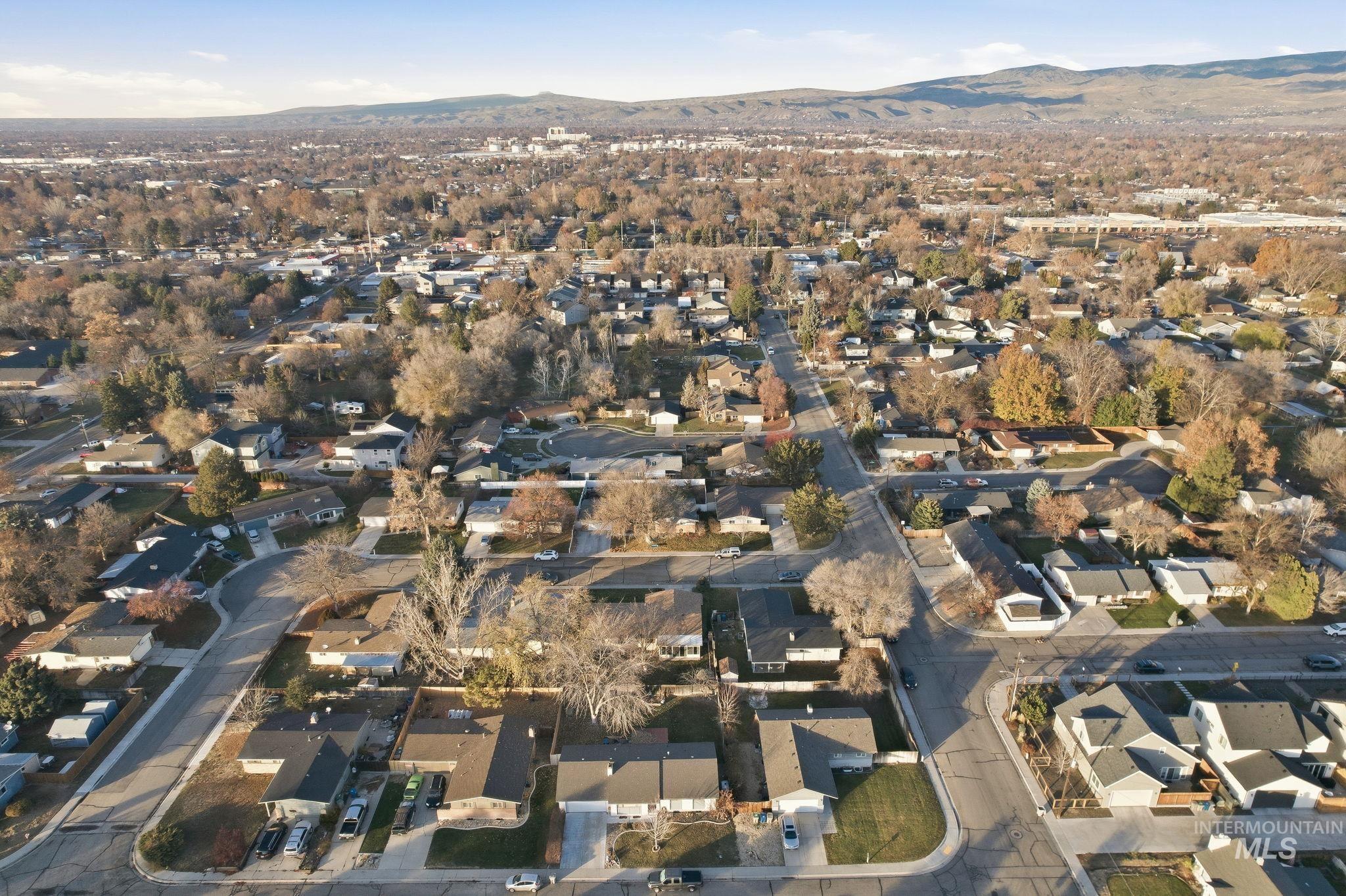 Aerial view of property and surrounding area featuring a mountainous background and nearby suburban area