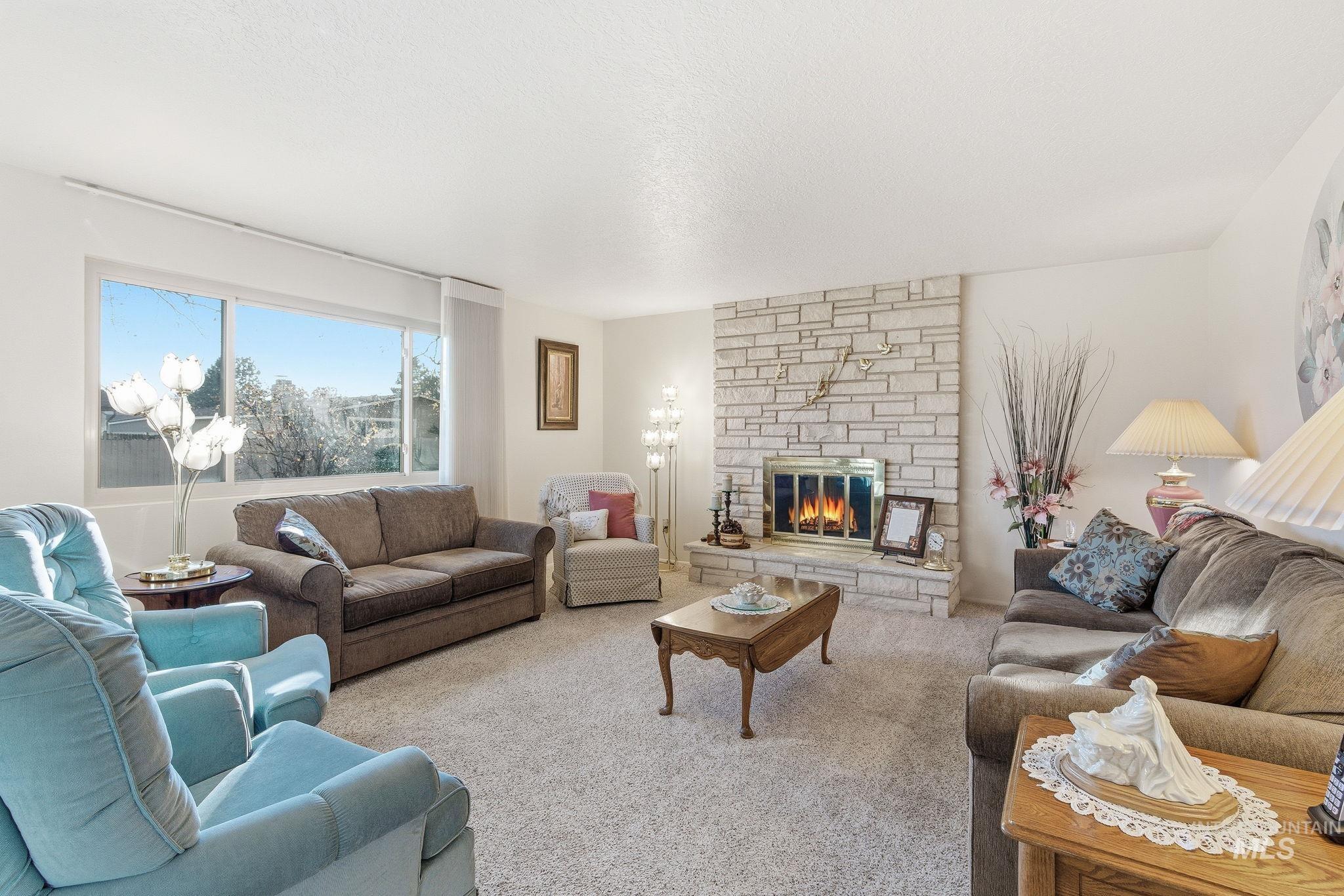 Carpeted living area featuring a fireplace and a textured ceiling