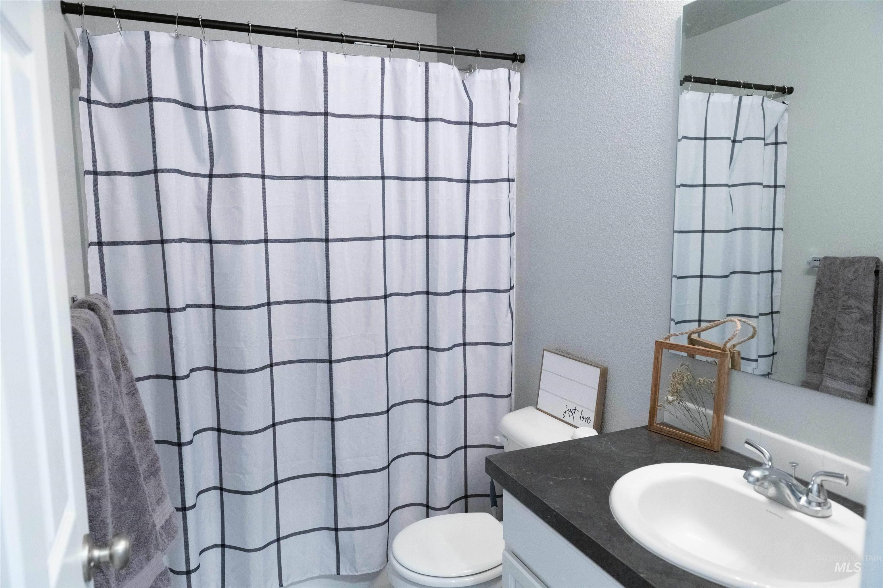 Full bath featuring vanity, a textured wall, and curtained shower