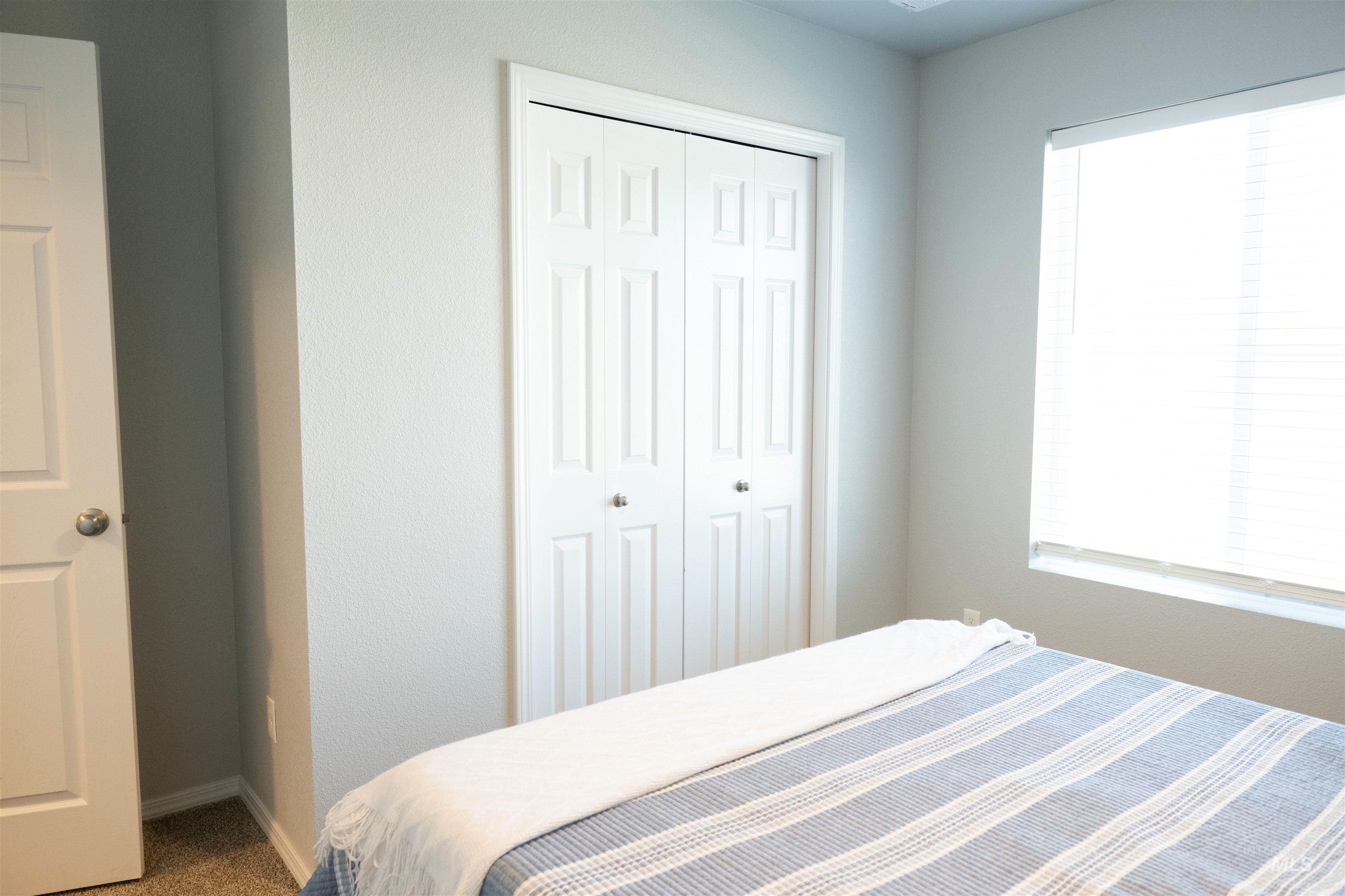 Bedroom featuring a closet, multiple windows, and carpet flooring