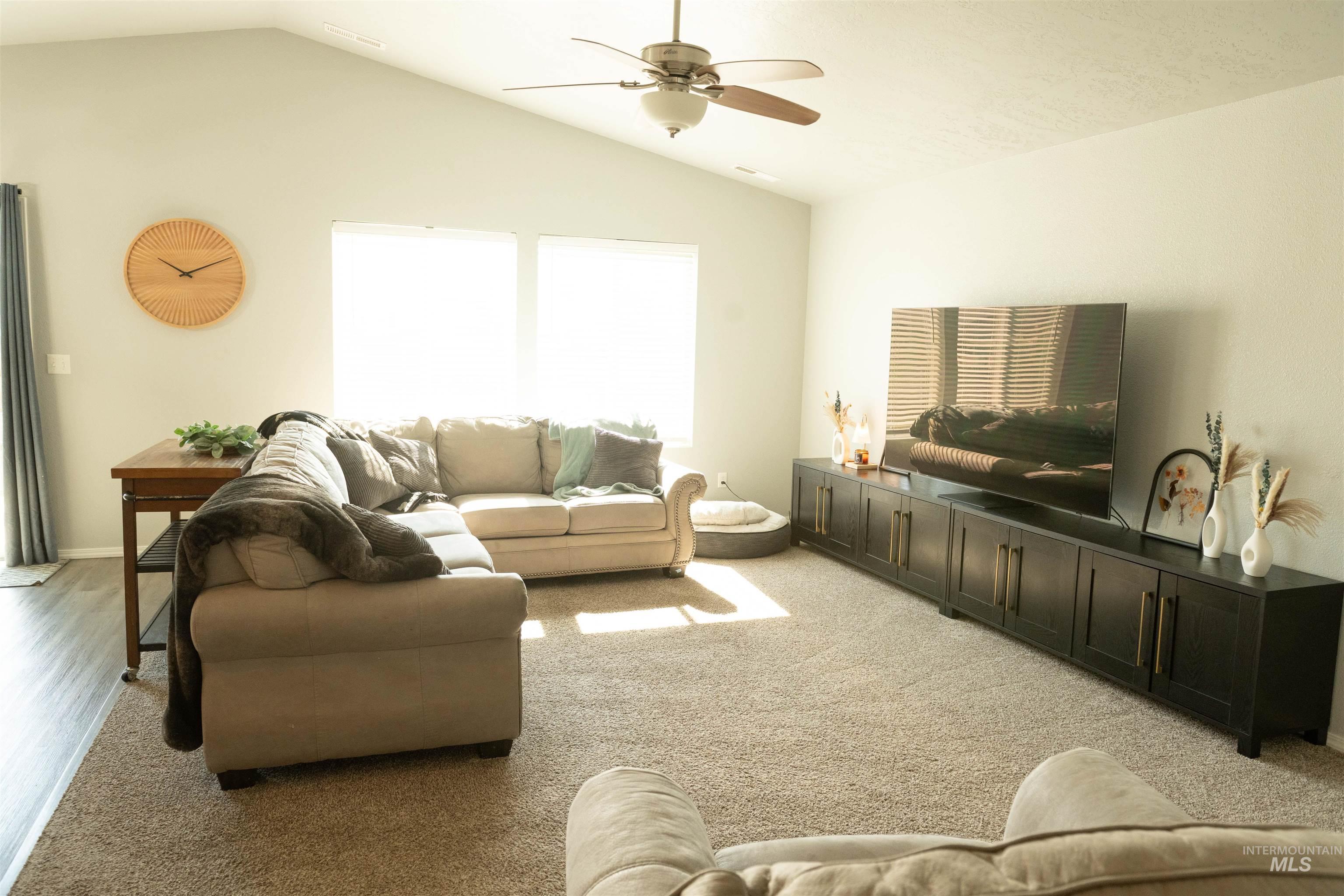 Living room featuring lofted ceiling, light colored carpet, and a ceiling fan